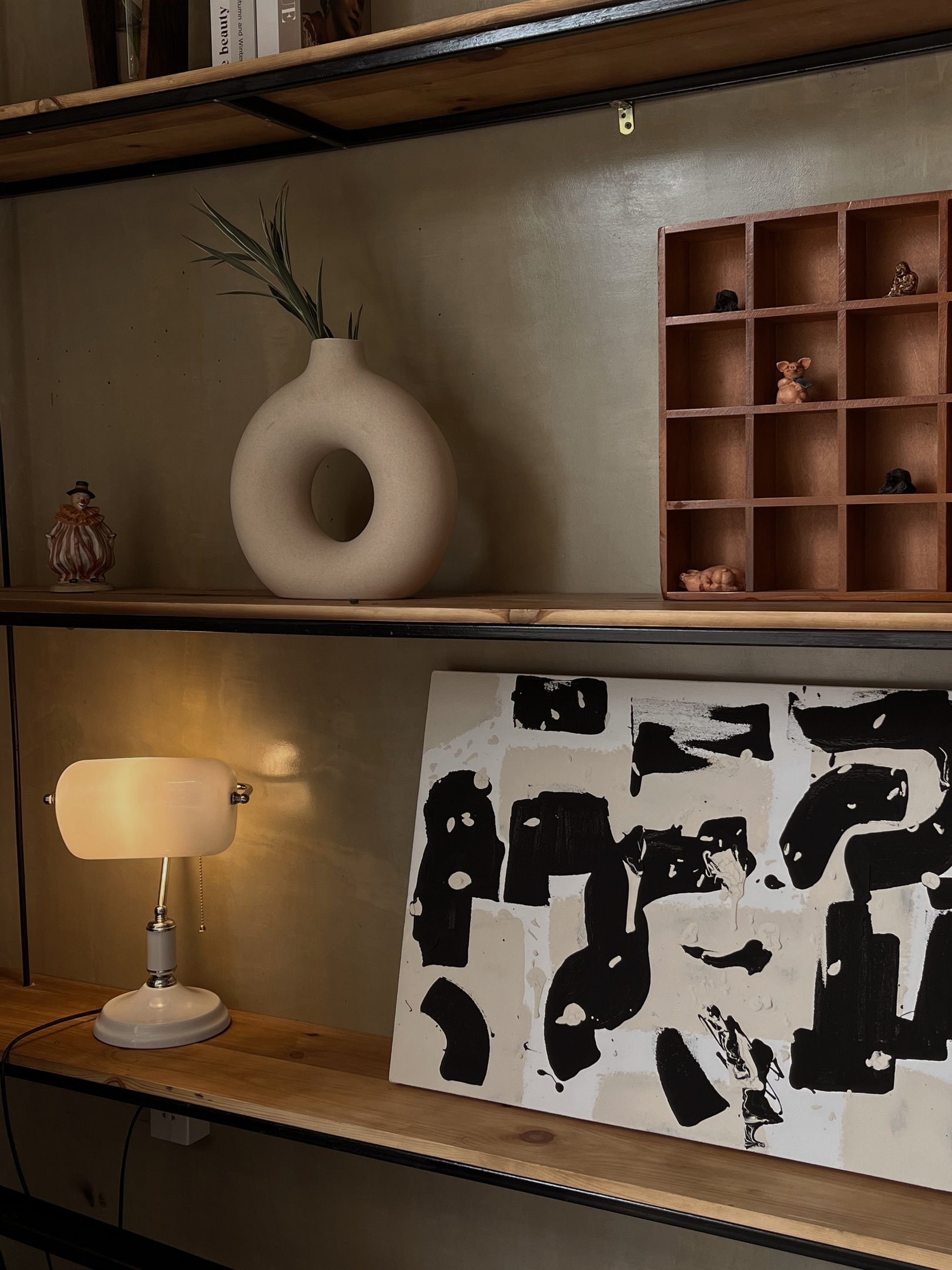 Erros de decoração aparecem no uso de objetos dispersos como vaso moderno bege, luminária vintage e quadro abstrato