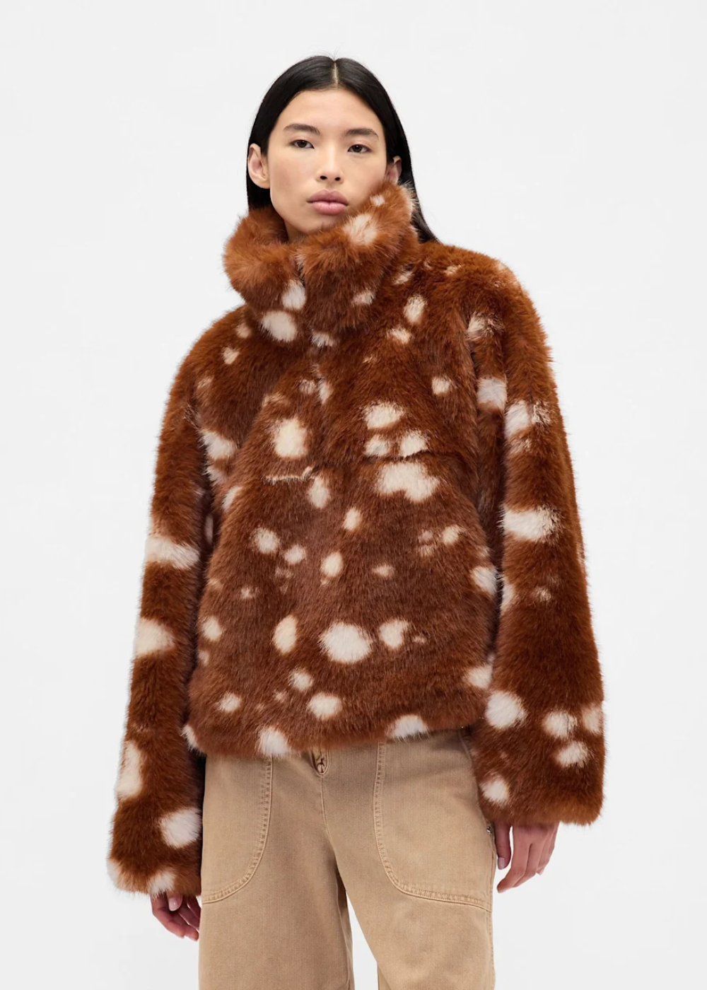 Modelo posa com casaco peludo de gola alta e estampa de cervo em tons terrosos.