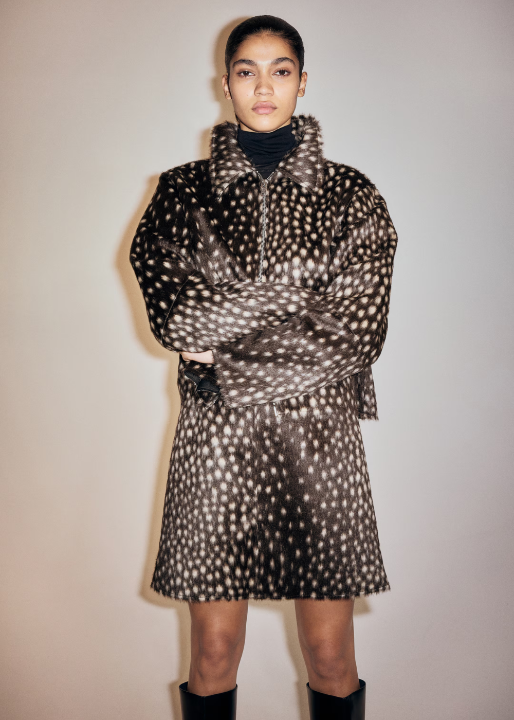 Modelo posa com jaqueta e saia de tecido aveludado em estampa de cervo marrom e branco.