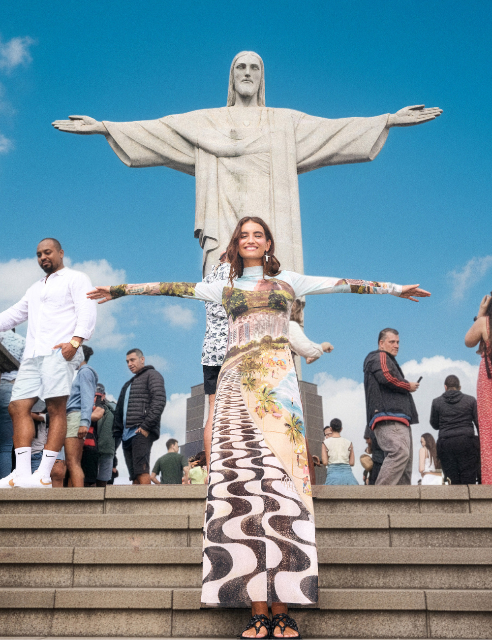 Modelo posa com vestido longo estampado com paisagem do calçadão de Copacabana, sob o Cristo Redentor no Rio de Janeiro.