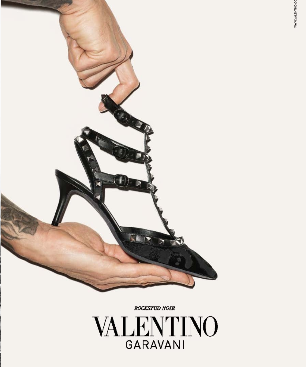 Sandália preta Valentino Rockstud em couro verniz com tiras e spikes metálicos, exibida com elegância e modernidade.