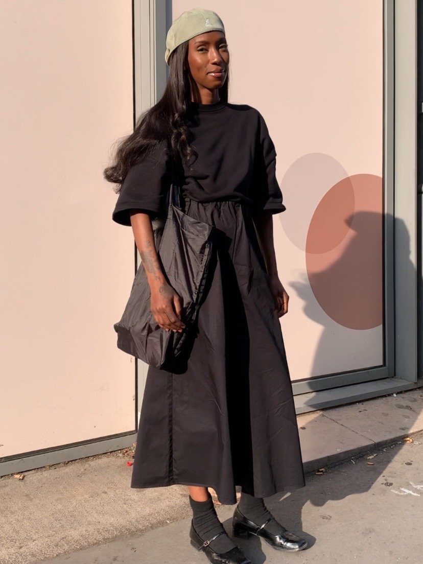 Modelo posa com boina kangol verde clara de tecido, vestido preto longo de algodão, bolsa oversized e sapatos pretos