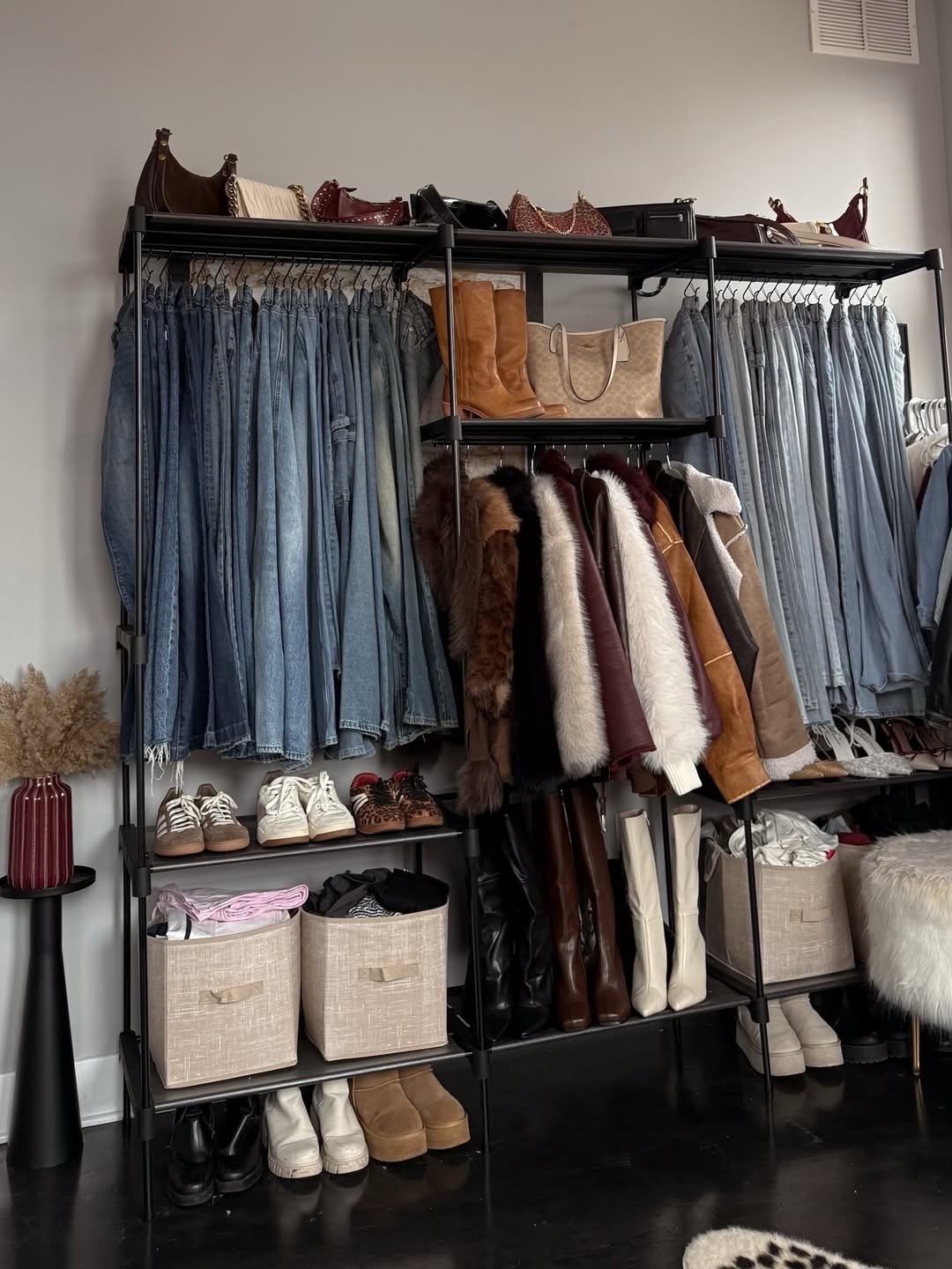 Closet organizado com calças jeans em tons variados, casacos de pelúcia e couro, botas e bolsas em cores neutras que