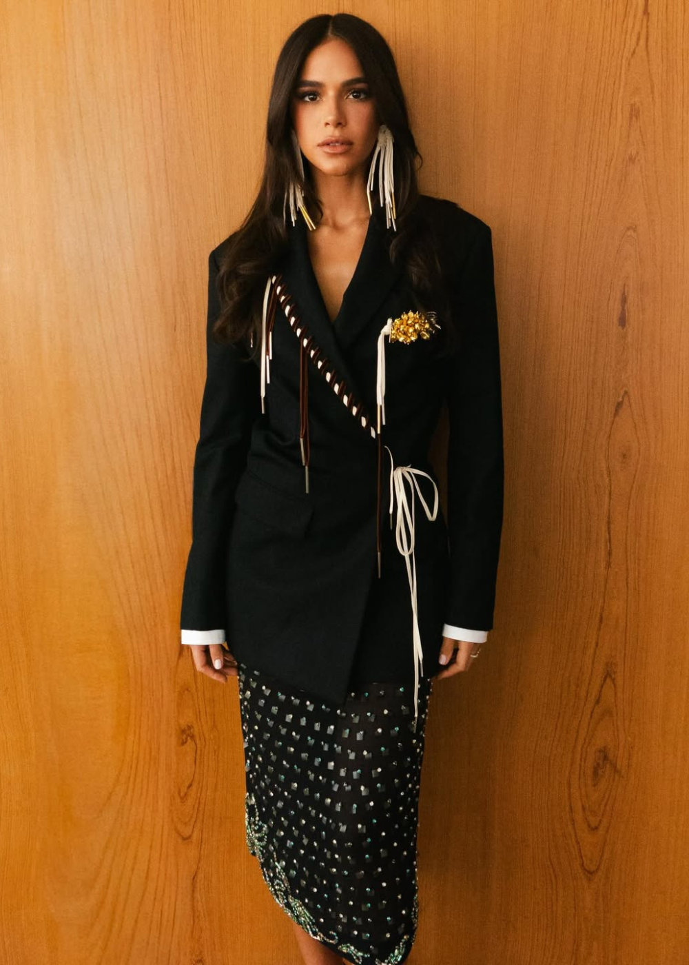 Bruna Marquezine posa com blazer preto estruturado e detalhes em tiras brancas, combinando saia midi preta com aplicações.