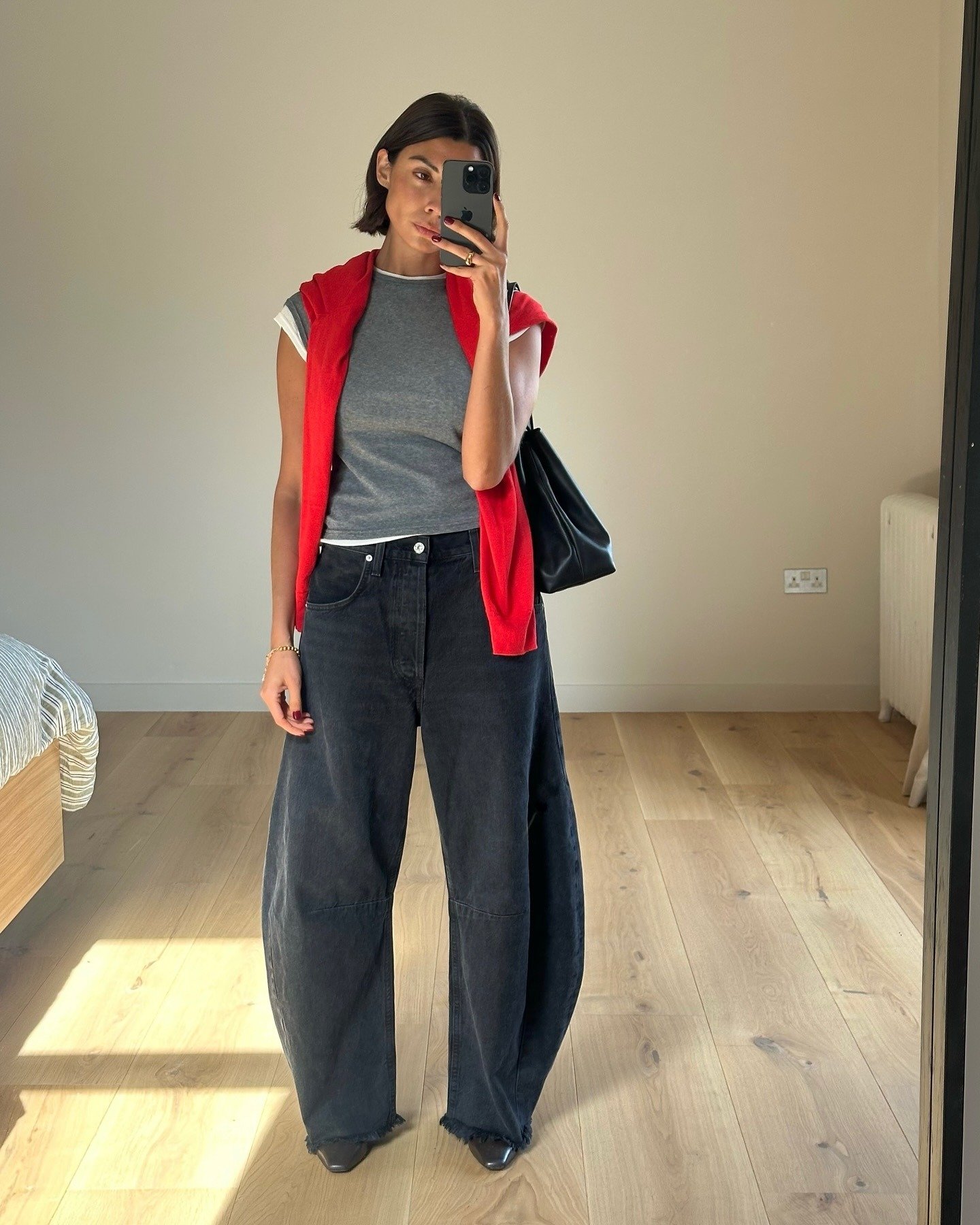 Modelo posa em looks confortáveis e estilosos com camiseta cinza justa, jeans preto wide leg e suéter vermelho sobre os