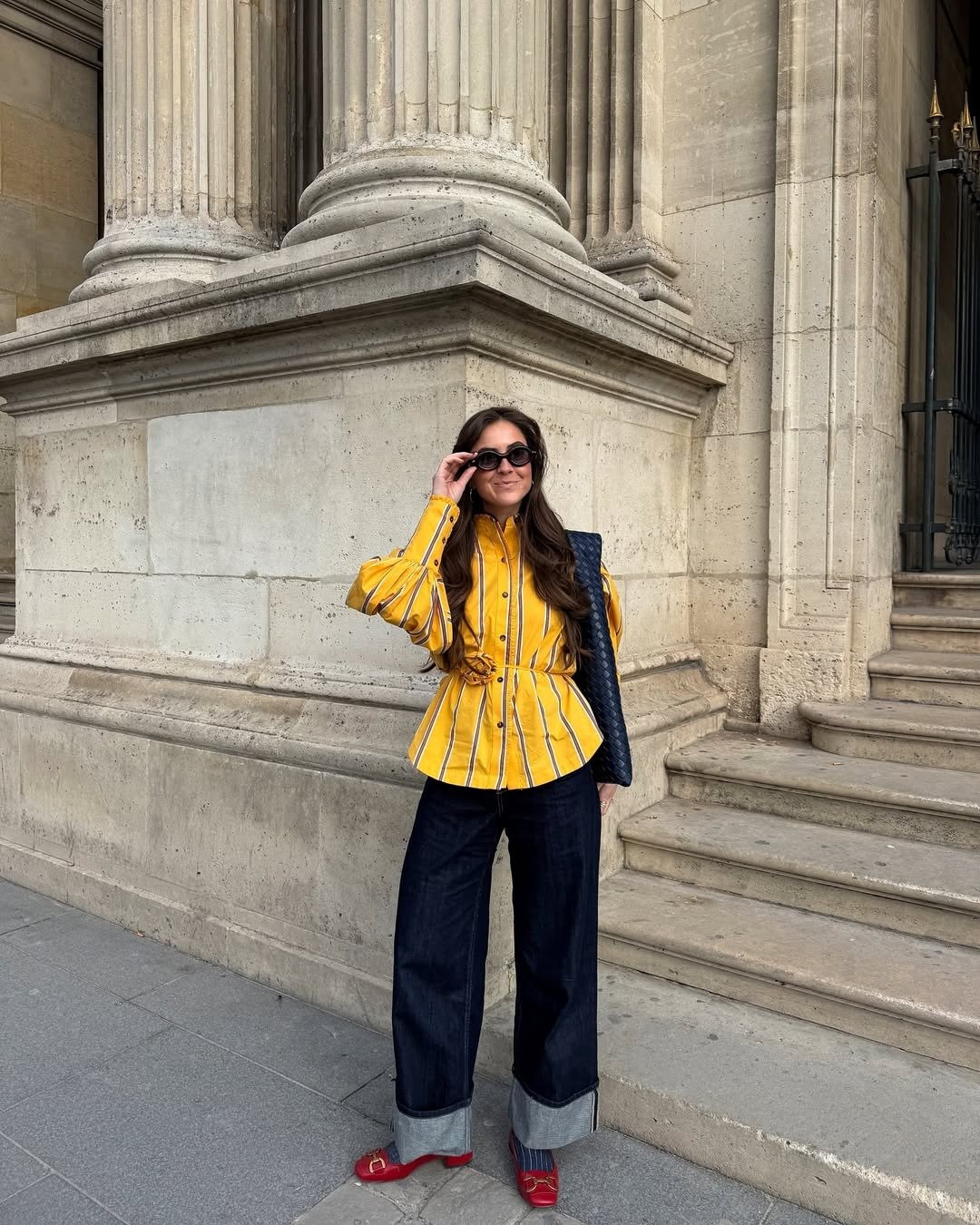 Modelo posa com looks fáceis e estilosos usando camisa amarela listrada de algodão estruturada, calça jeans escura ampla com