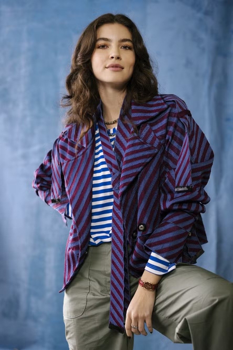 Lorena e Juquinha exibem estilo casual com jaqueta oversized listrada roxa e azul, camiseta listrada azul e branca e calça