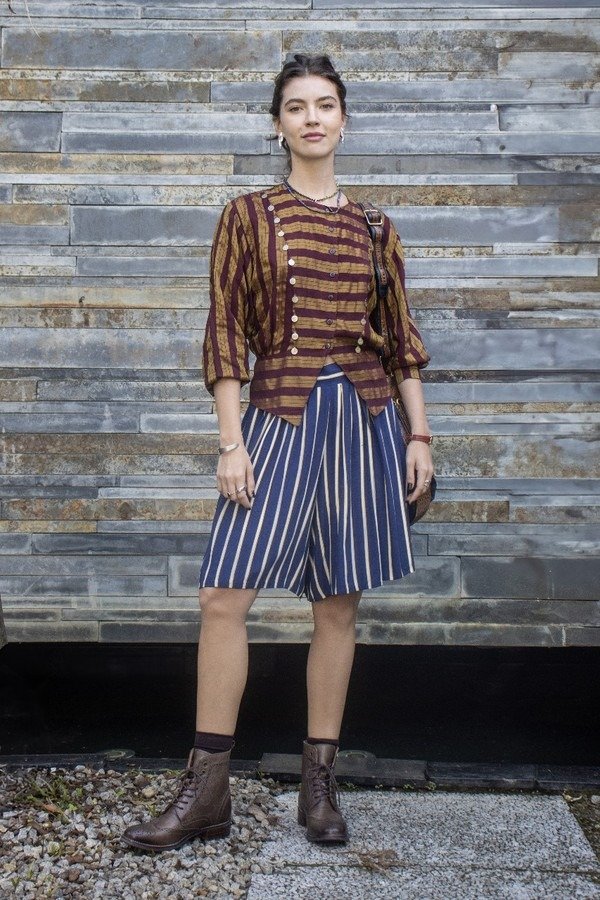 Lorena e Juquinha exibem estilo moderno com blusa listrada vinho e mostarda de botões, bermuda azul com listras brancas