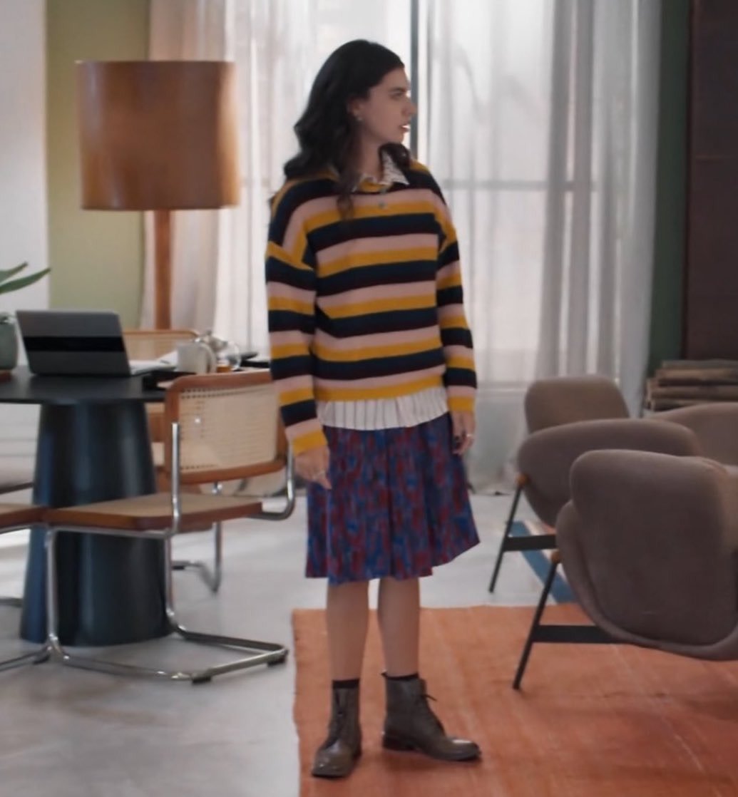 Lorena e Juquinha exibem estilo casual com suéter listrado amarelo, rosa e preto, saia plissada azul e botas de couro