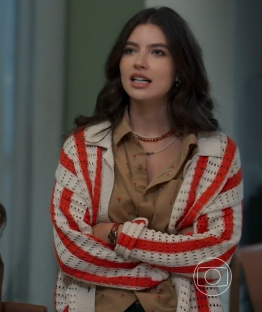 Lorena e Juquinha exibem estilo casual com camisa bege estampada e cardigan tricô listrado vermelho e branco, em postura