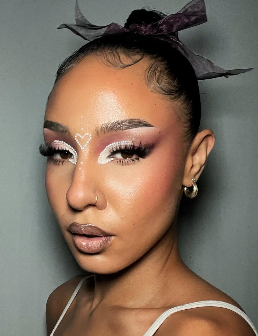 Maquiagens de Carnaval com delineado branco pontilhado em formato de coração, sombra rosa esfumada e batom nude brilhoso.