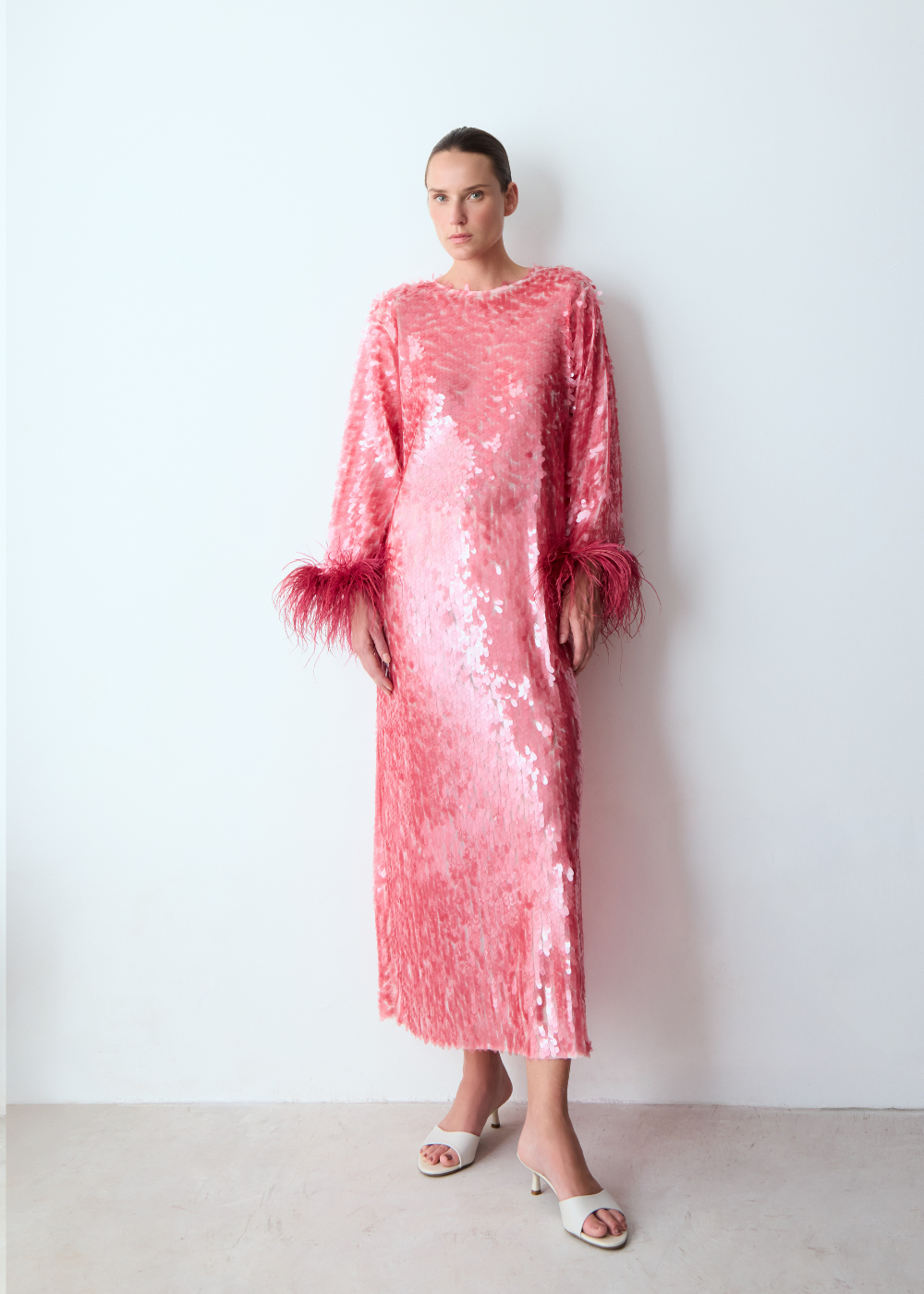 Modelo posa com camiseta branca oversized e saia rosa de paetês e plumas, combinando conforto e brilho em drop de carnaval