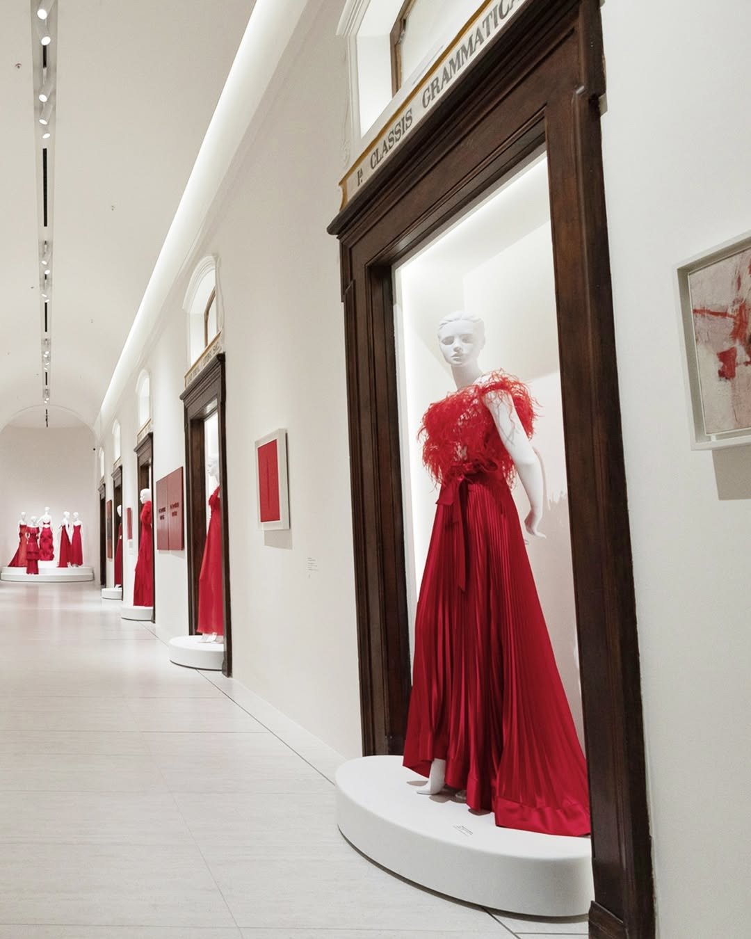 Valentino exibe vestidos vermelhos com plumas e tecidos fluidos em modelagens elegantes, criando atmosfera sofisticada e