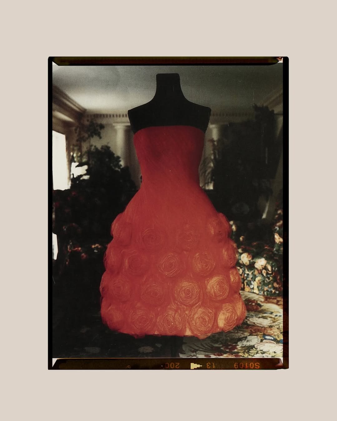 Vestido Valentino tomara que caia em vermelho vibrante com saia volumosa adornada por rosas em tecido texturizado, cenário