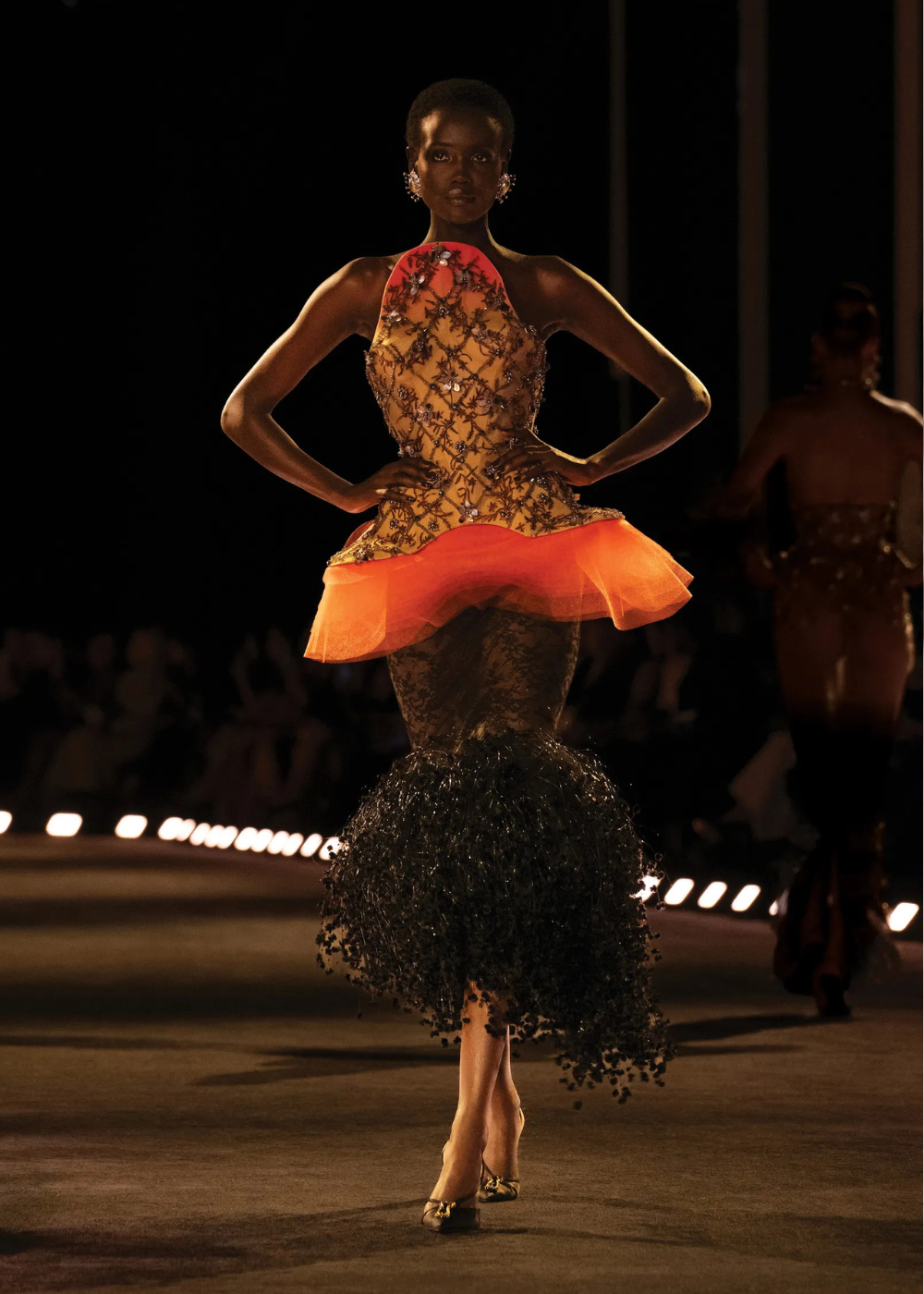 Modelo posa com vestido de alta-costura primavera 2026 que mistura corpete bordado em tons quentes, saia volumosa em tule