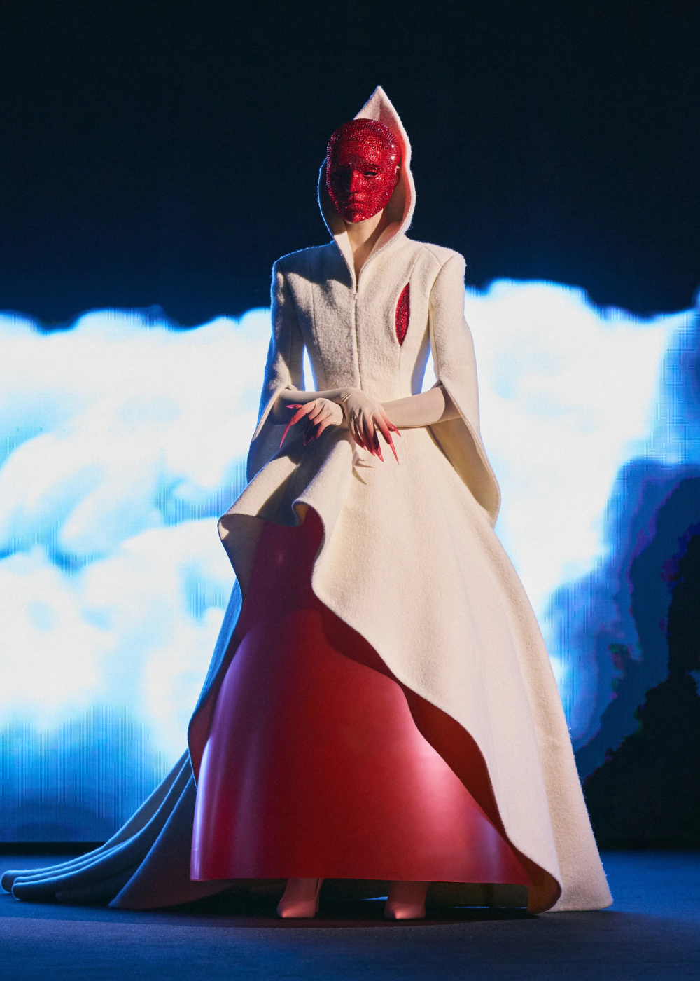 Modelo posa com vestido de alta-costura primavera 2026 que combina capa estruturada off-white em tecido texturizado e saia