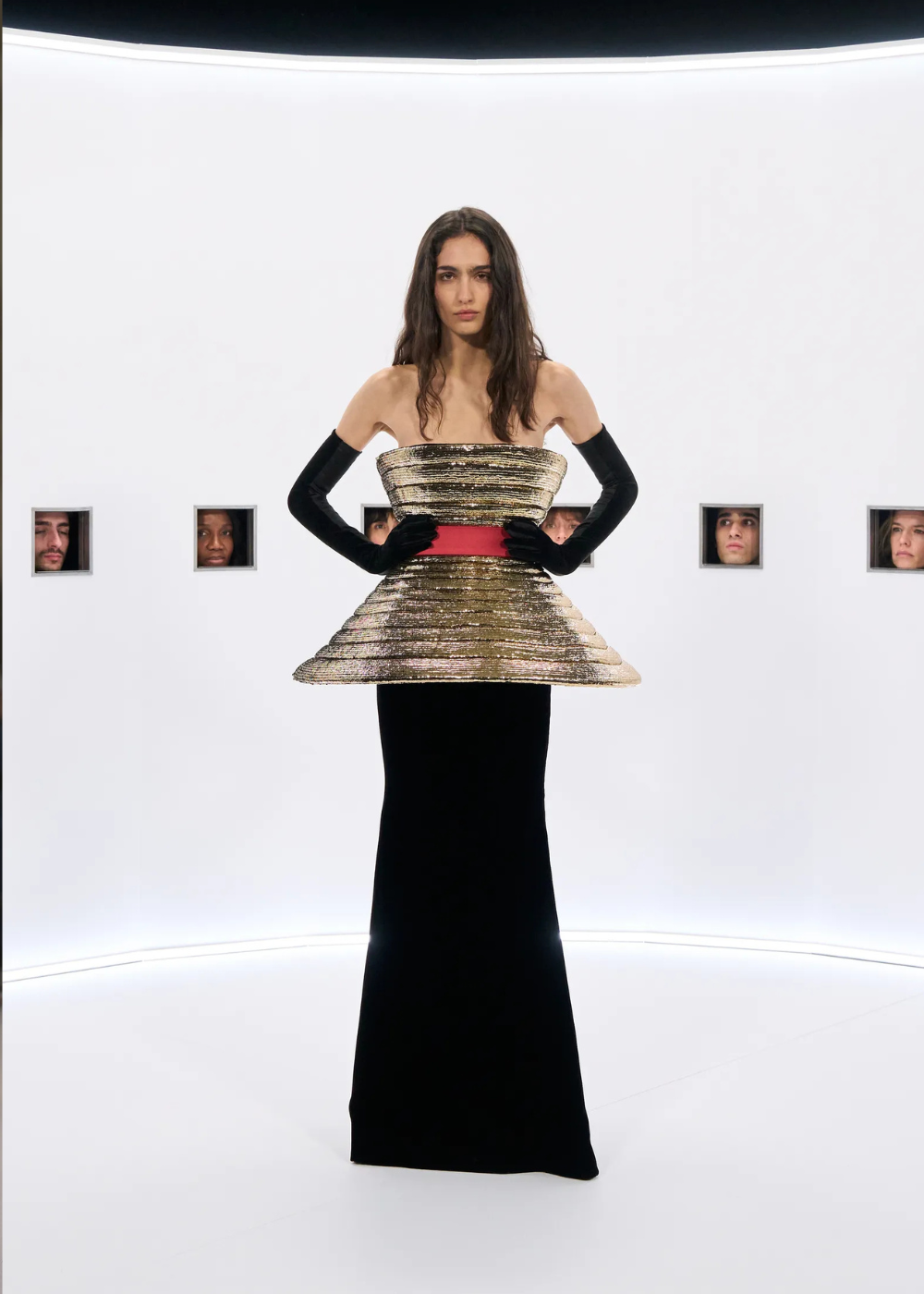 Modelo posa com vestido de alta-costura primavera 2026 que combina corpete estruturado dourado, saia preta longa e luvas