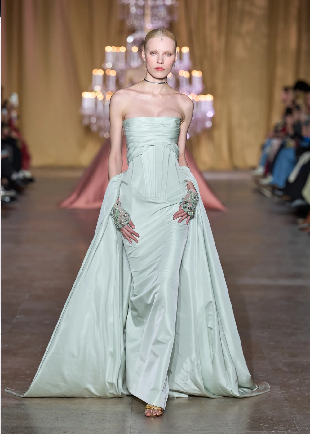 Modelo posa com vestido tomara que caia em tecido acetinado verde-menta, corset estruturado, capa fluida e luvas bordadas,