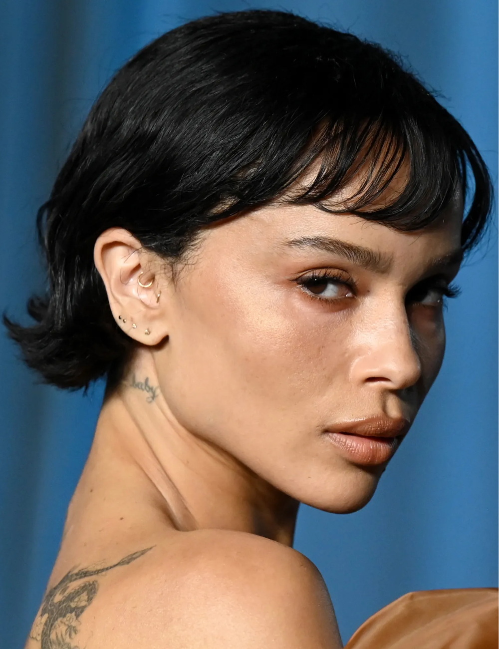 Modelo posa com olhar intenso e maquiagem natural em tons terrosos, evidenciando tendências de beleza 2026.