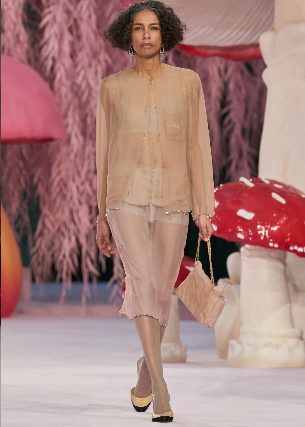 Modelo caminha com postura confiante usando conjunto de alta-costura primavera 2026 em tecidos translúcidos nude, com