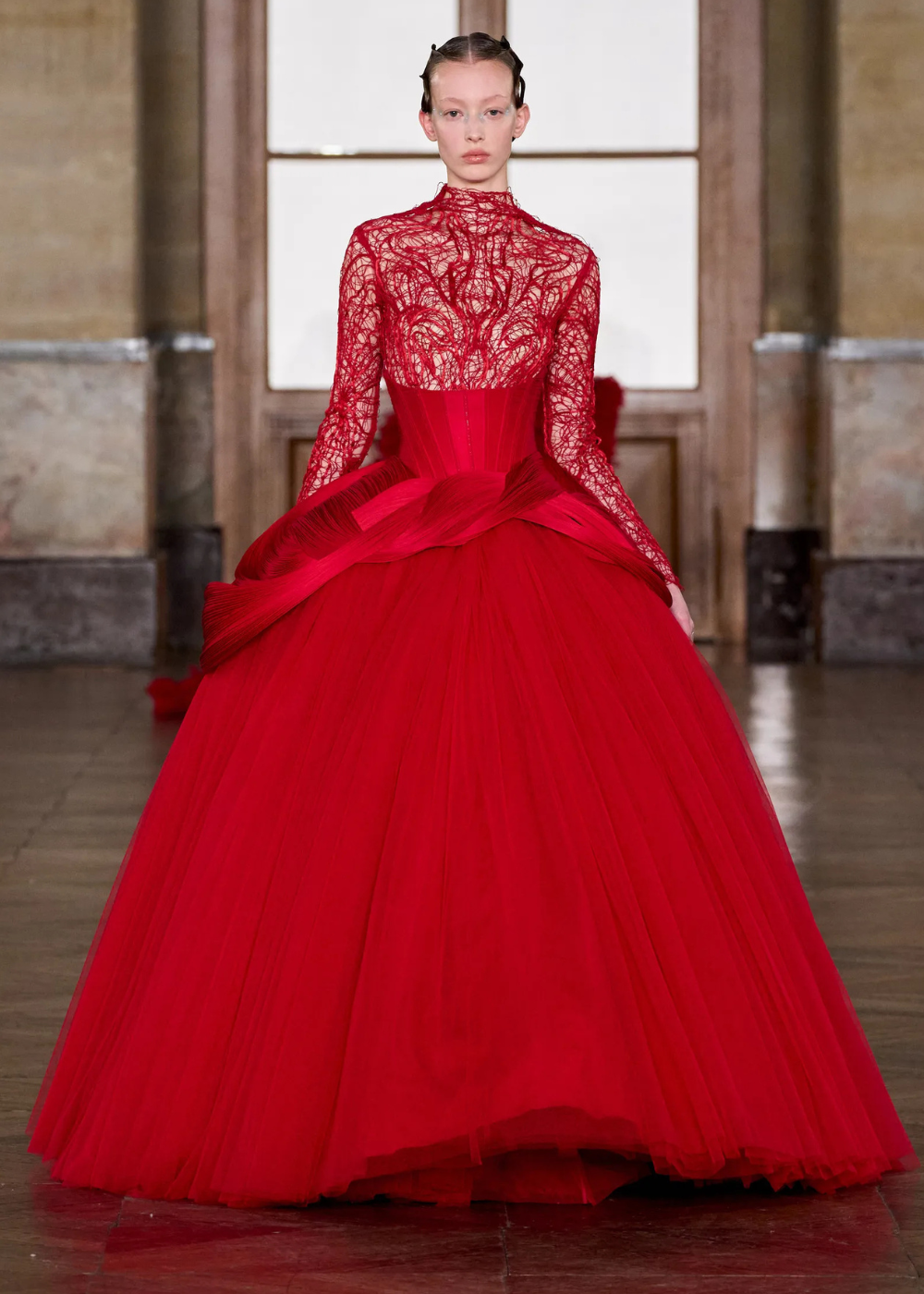 Modelo posa com vestido vermelho vibrante de alta-costura primavera 2026, combinando corpete estruturado, renda delicada e