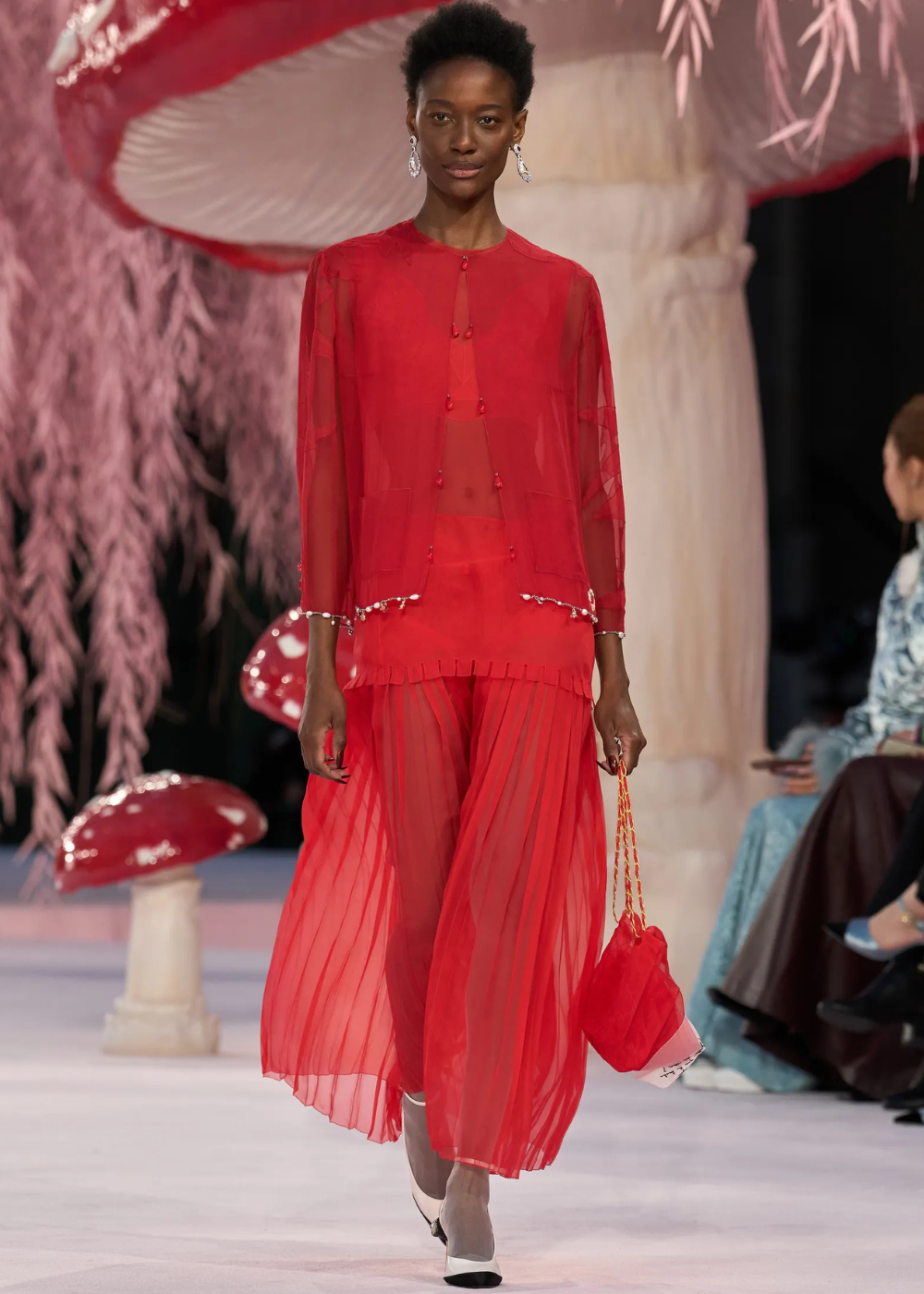 Modelo caminha com postura confiante usando conjunto vermelho de alta-costura primavera 2026, com transparência, tecidos