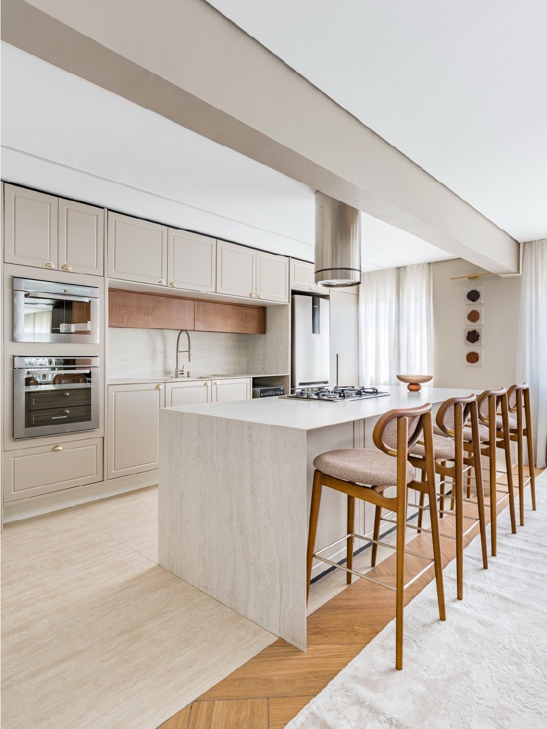 Tendências de arquitetura para cozinha revelam ilha central em mármore claro, armários bege com puxadores dourados