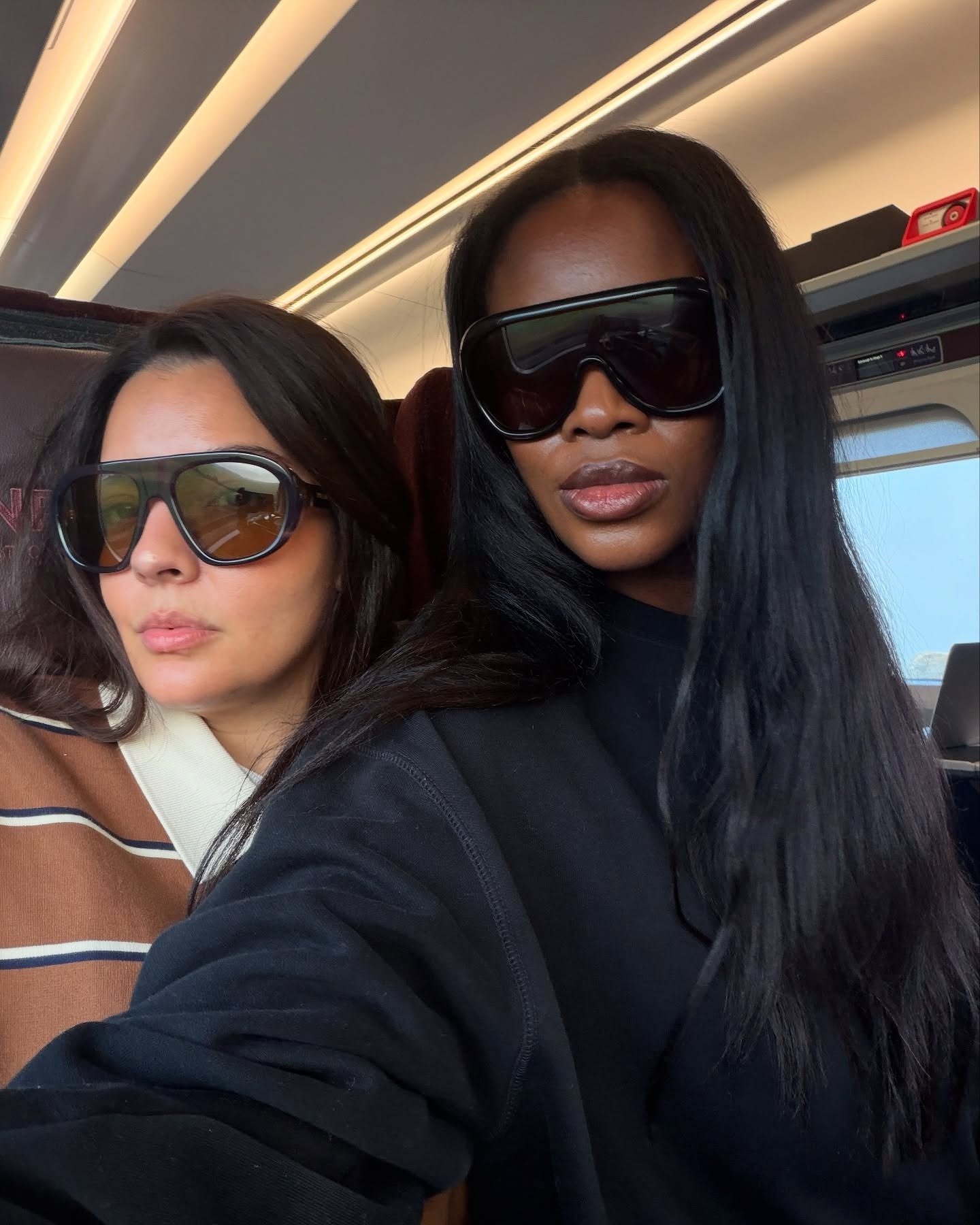 Duas mulheres posam com óculos oversized em acetato preto, destacando acessórios tendência de 2026 com estilo urbano