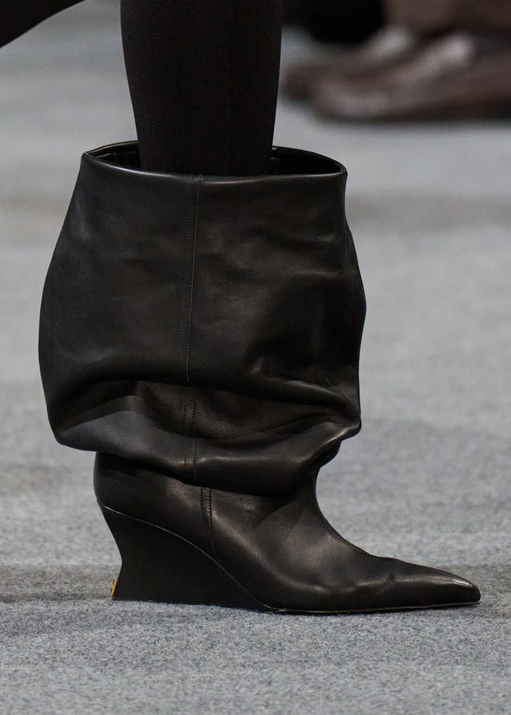 Bota slouchy preta em couro com salto anabela médio e bico fino, combinando estilo moderno e conforto urbano.