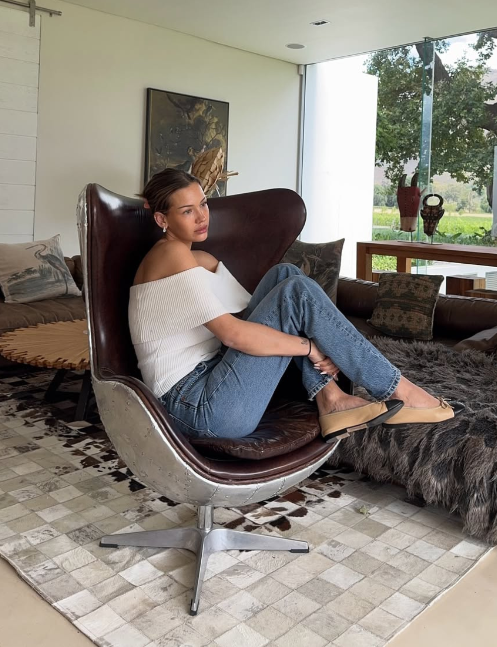 Modelo de calça jeans elegante com modelagem reta e lavagem azul clássica, combinada a blusa ombro a ombro branca.