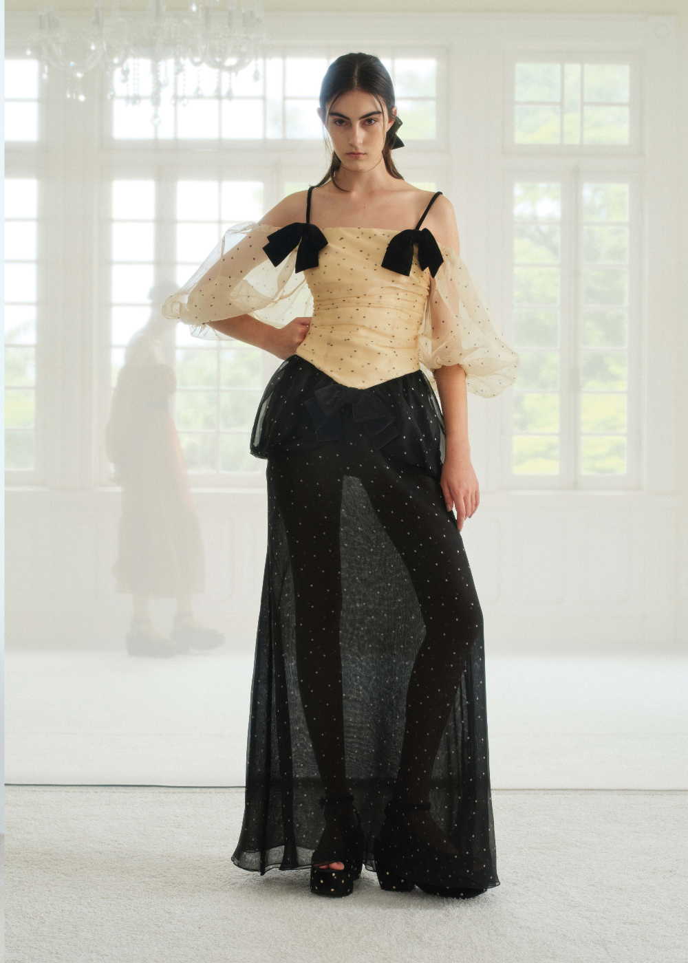 Modelo posa com vestido CRIS BARROS em tule poá bege e preto, mangas bufantes e laços, combinando transparência e elegância