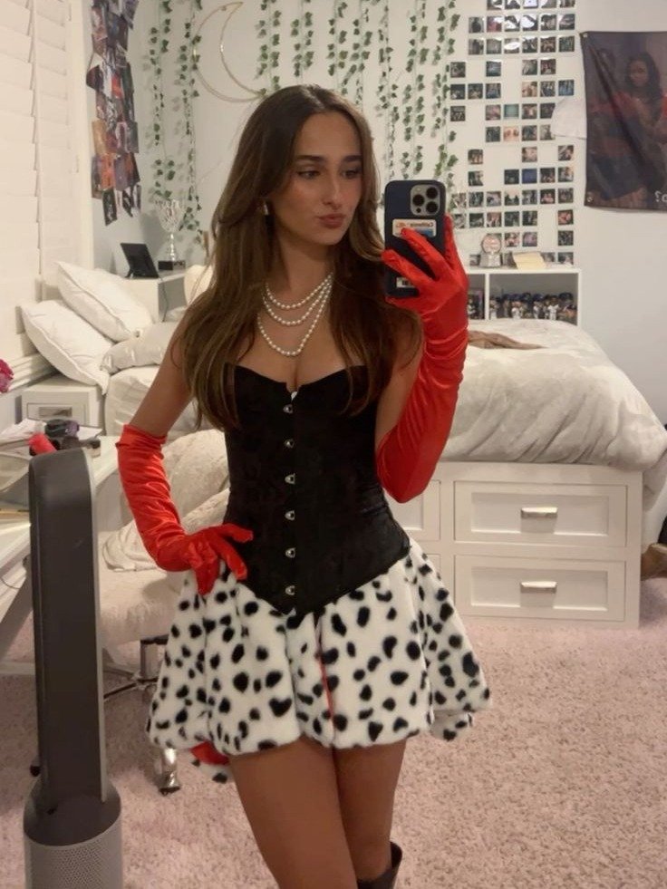 Fantasia de carnaval com corpete preto estruturado, saia branca de pelo com manchas pretas, luvas vermelhas longas e colar