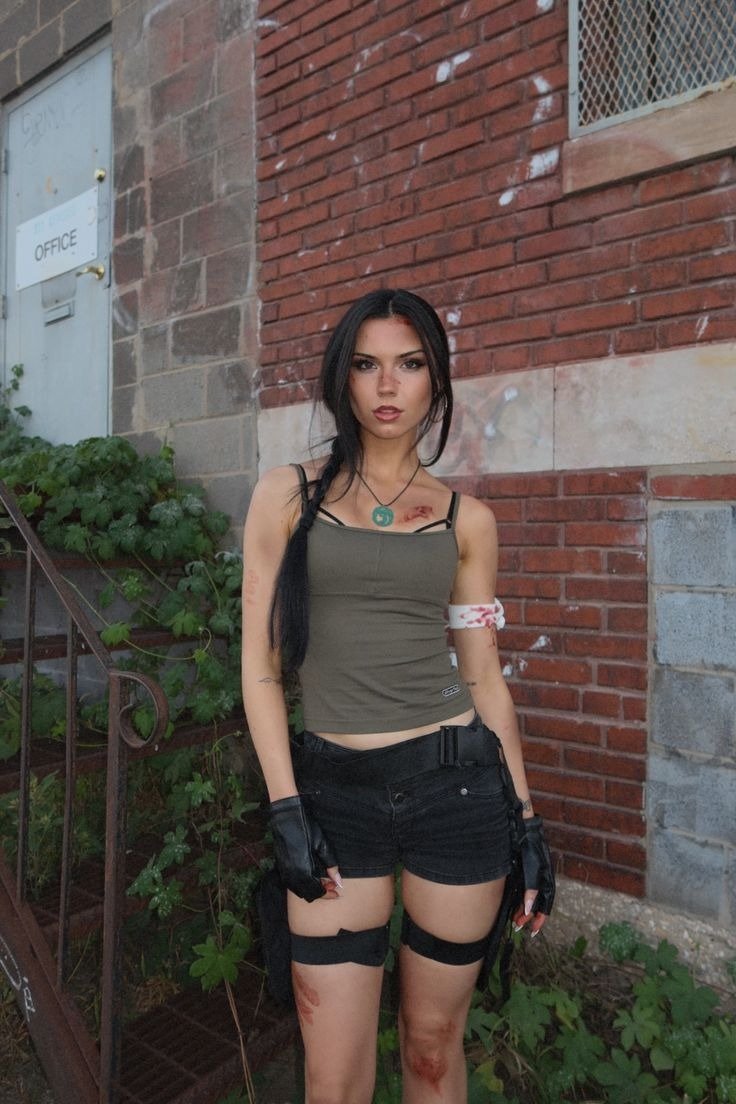Fantasia de carnaval com top verde militar, shorts pretos, luvas sem dedos e maquiagem que simula ferimentos