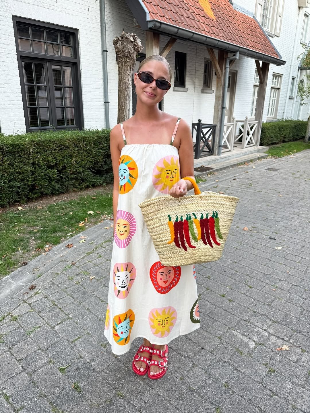 Modelo com vestido solto estampado em amarelo, laranja e rosa, bolsa de palha ilustrando perfumes cítricos femininos