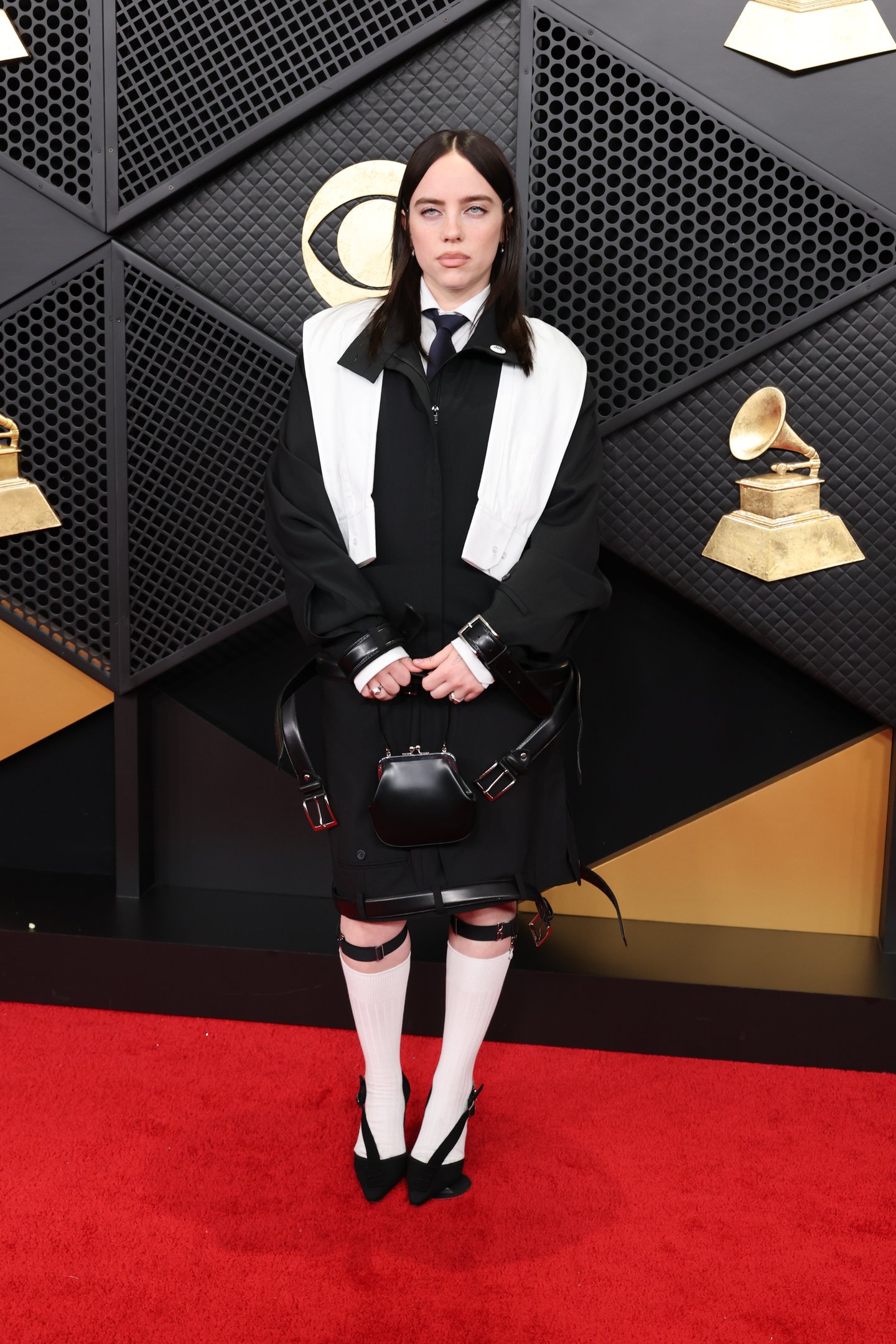 Artista posa no Grammy 2026 com look oversized preto e branco, mistura de alfaiataria e couro, meias longas brancas e clima