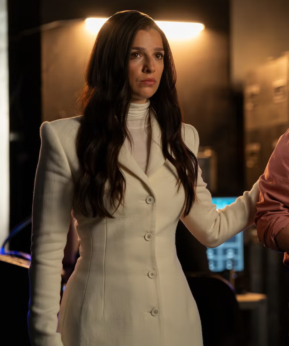 Na quarta temporada de Industry, mulher veste blazer branco estruturado com ombreiras e gola ampla, expressão séria em