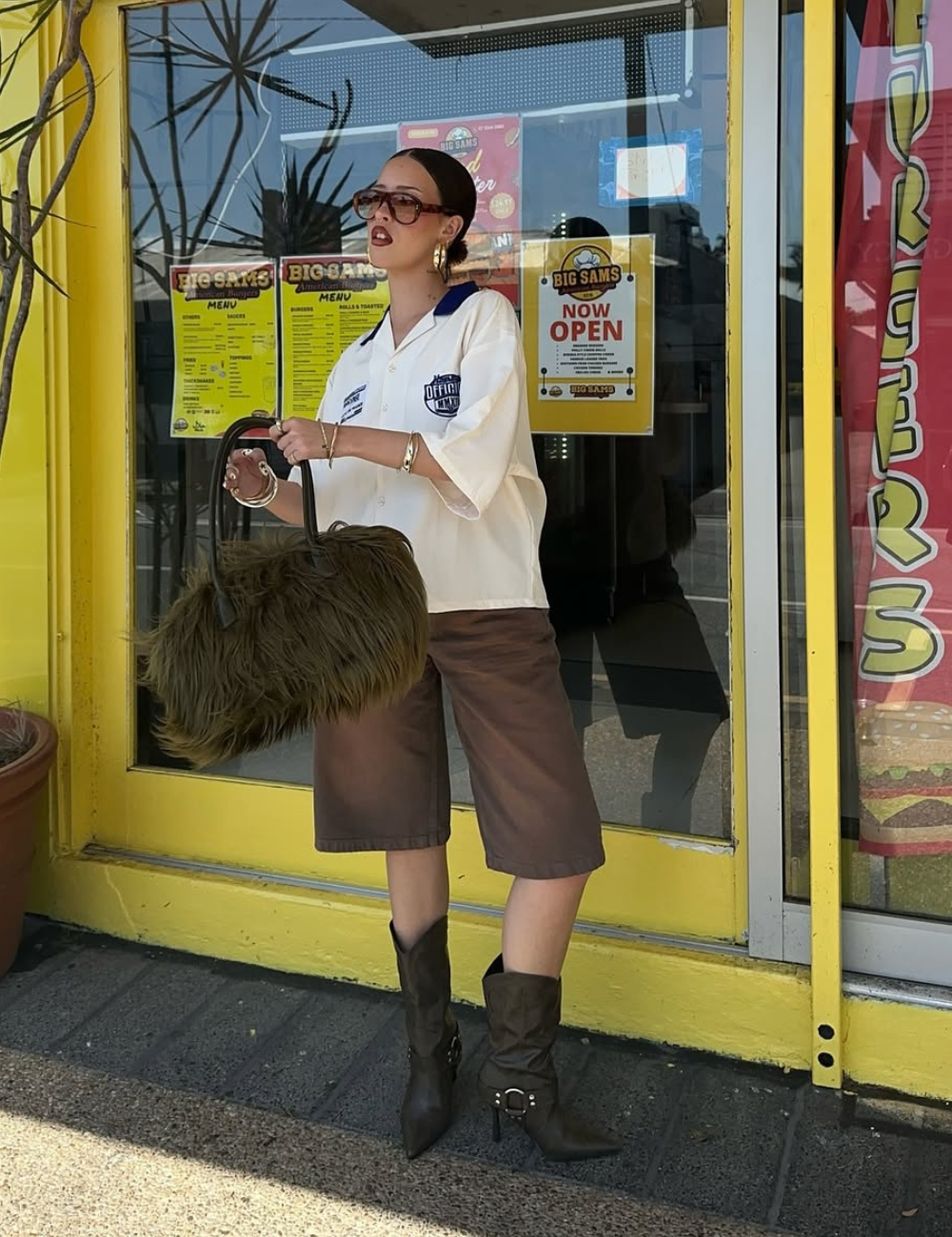 Look para o show do Bad Bunny com camisa oversized branca, bermuda marrom, bota de cano médio e bolsa peluda.