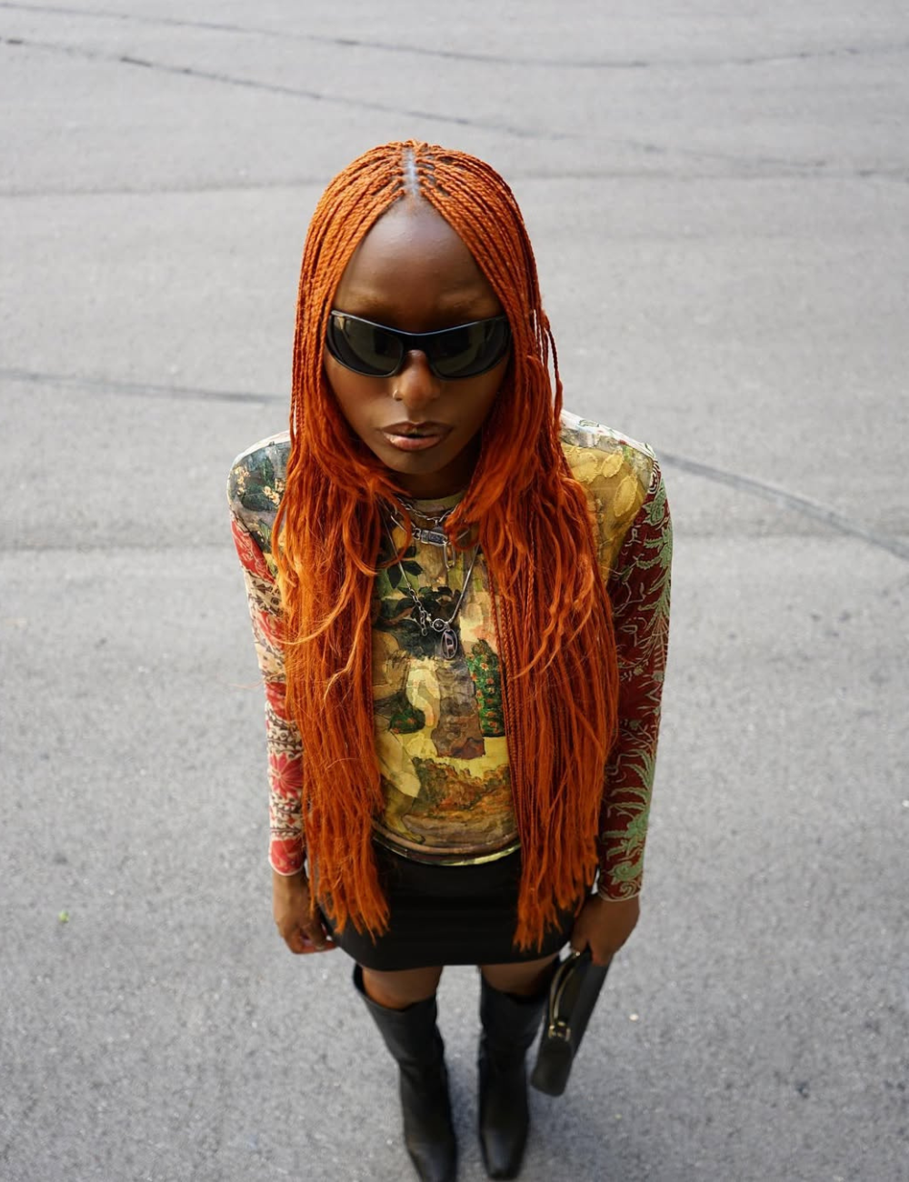 Look para o show do Bad Bunny com blusa manga longa estampada em tons terrosos, minissaia preta, botas de couro e acessórios.