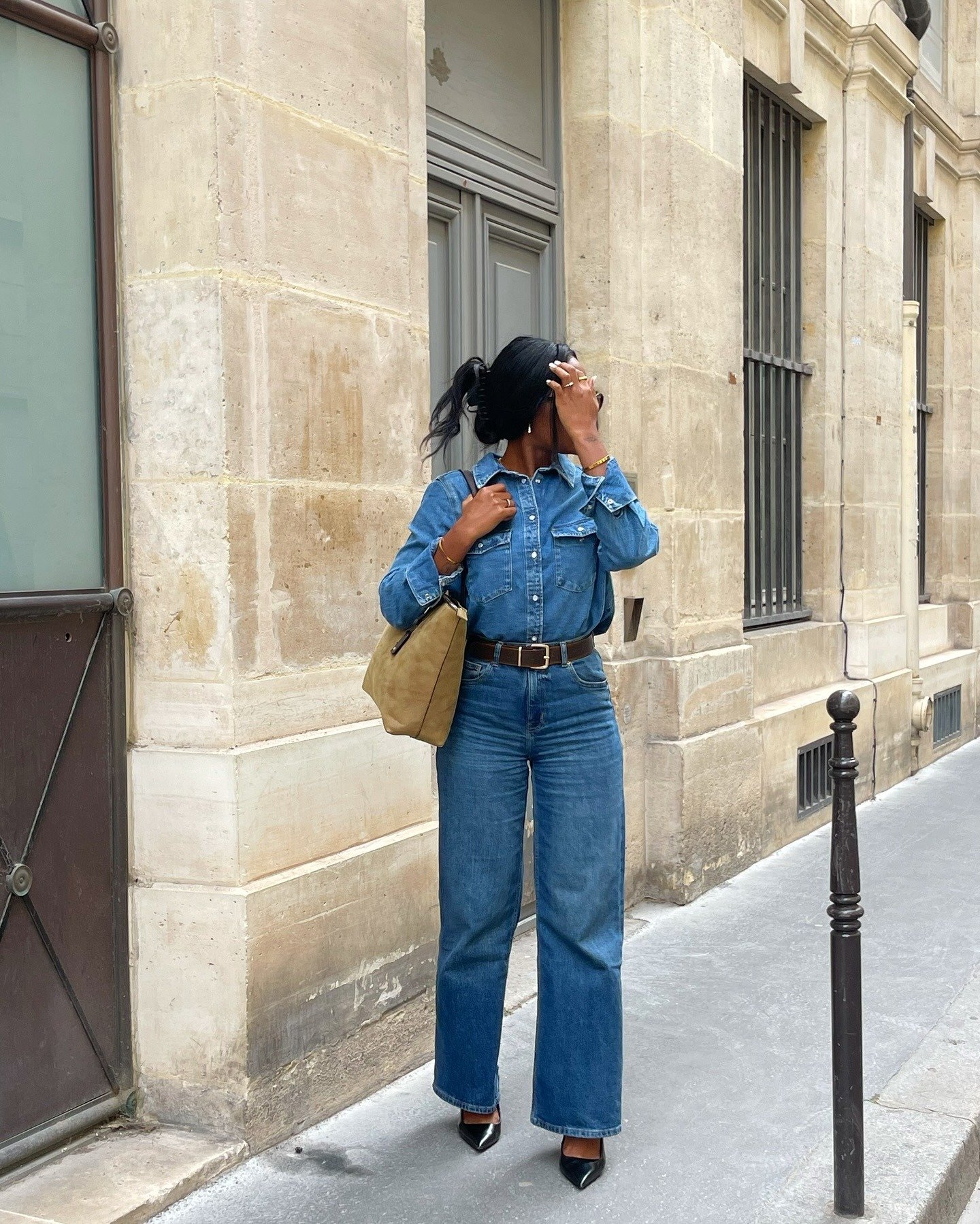 Look esporte fino feminino com calça jeans reta azul, camisa jeans, cinto marrom, scarpin preto e bolsa bege