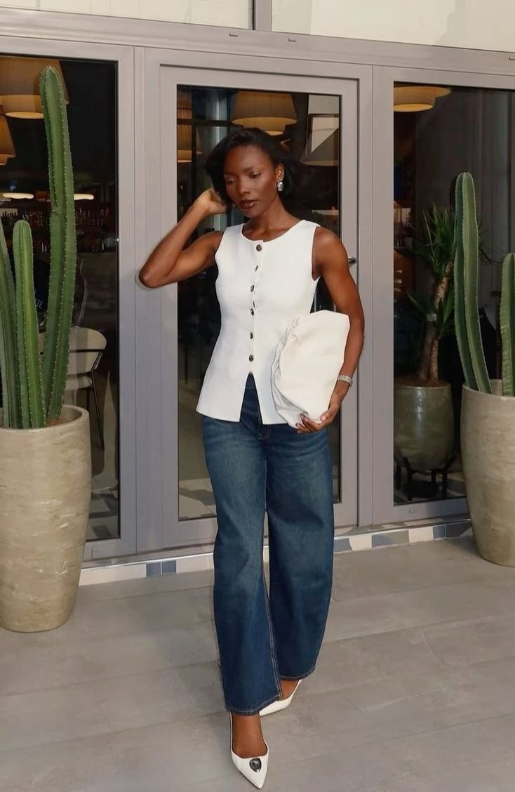 Look esporte fino feminino com calça jeans flare azul, blusa branca sem mangas com botões, scarpin e clutch brancos