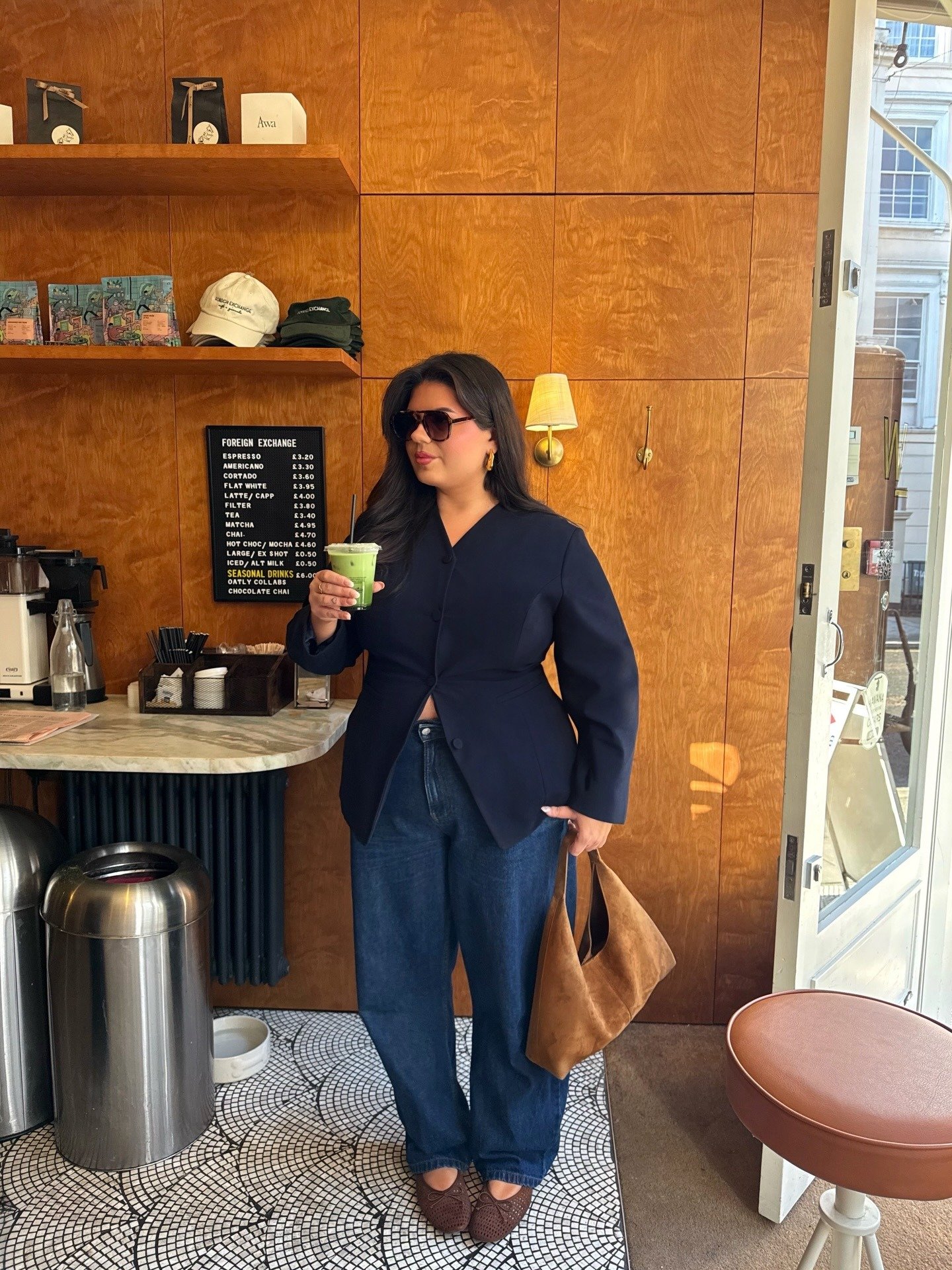 Look esporte fino feminino com calça jeans azul escuro de modelagem ampla, blazer preto estruturado, bolsa marrom em camurça