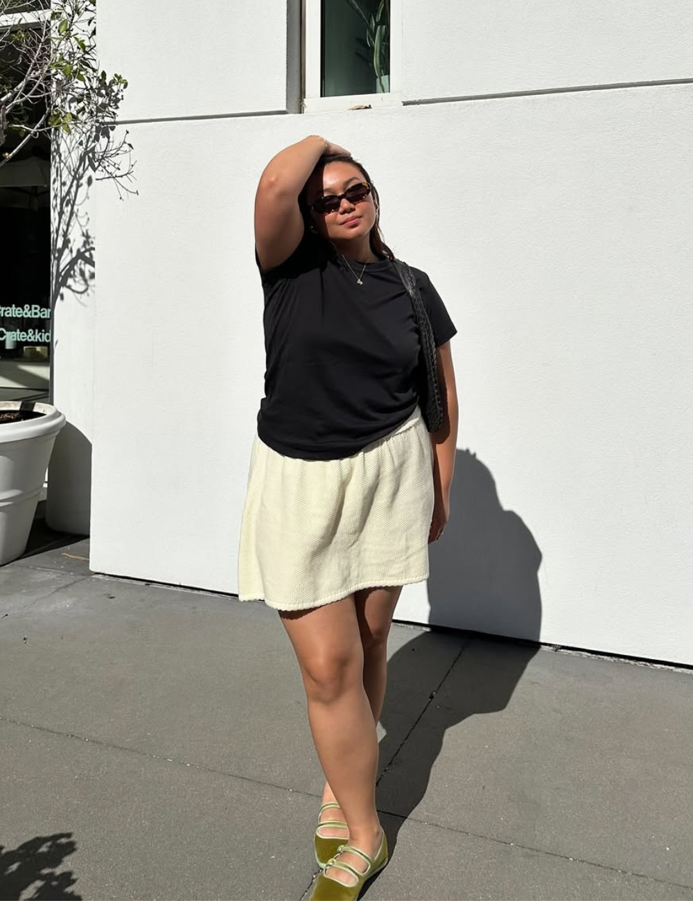 Looks com minissaia de tecido texturizado off-white, camiseta preta básica, bolsa tiracolo e sapato verde.