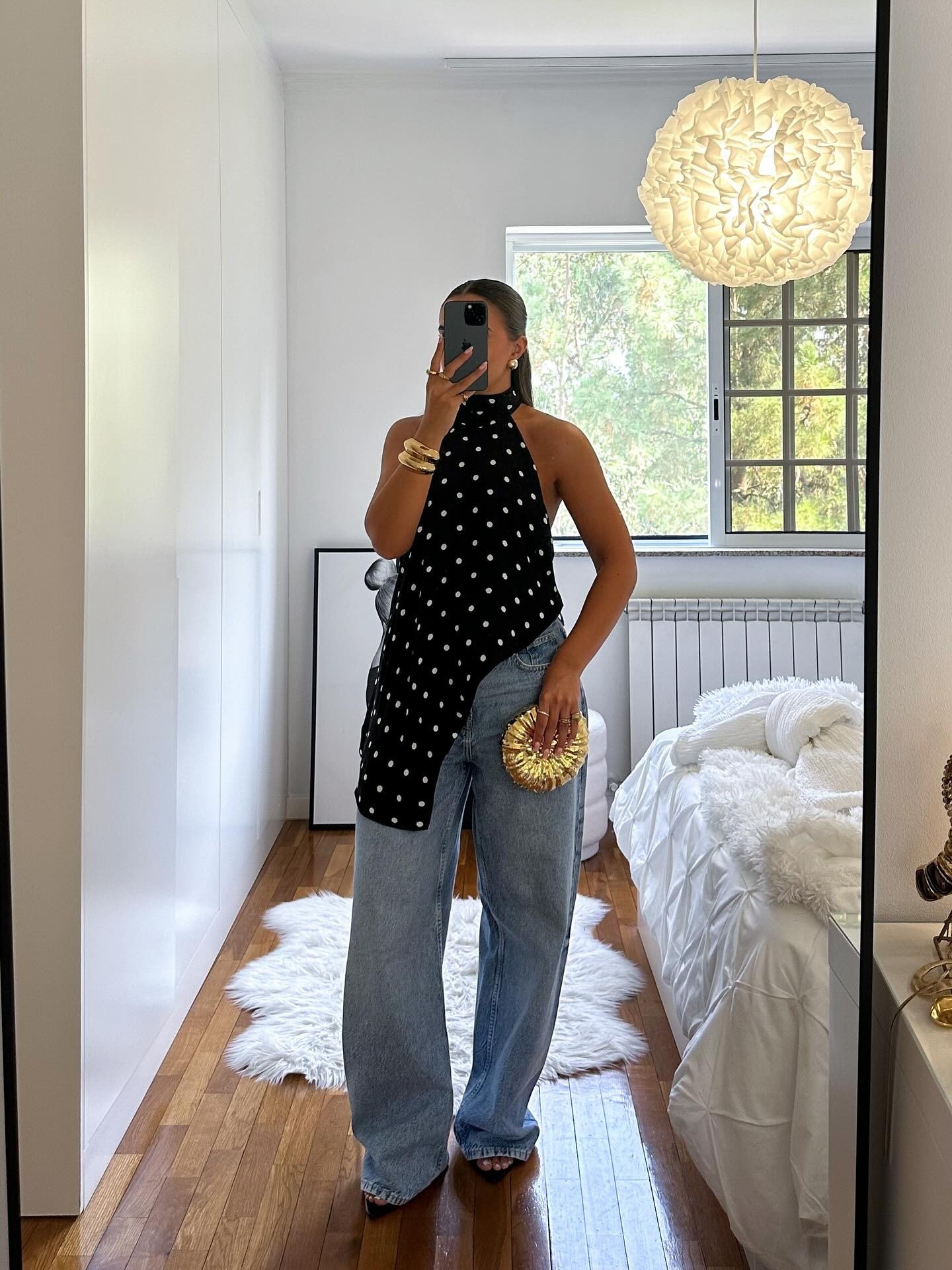 Modelo posa com looks lindos combinando blusa preta de poás assimétrica em tecido leve e jeans wide leg azul claro