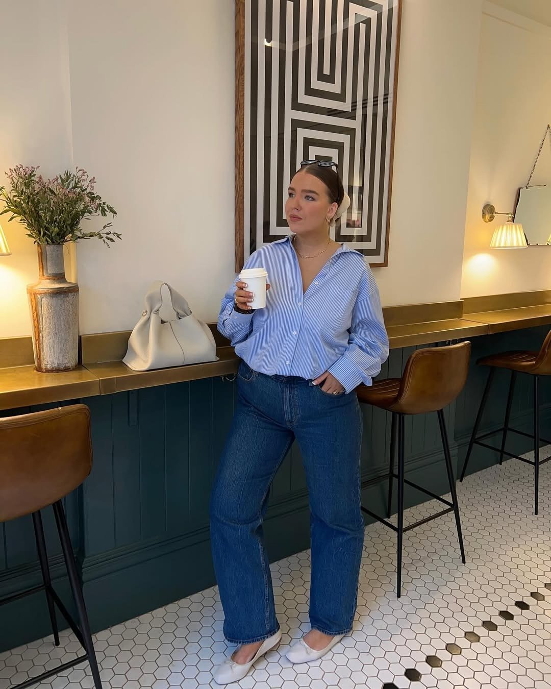 Modelo posa com looks lindos em camisa azul listrada oversized, jeans reto escuro e sapatilhas brancas