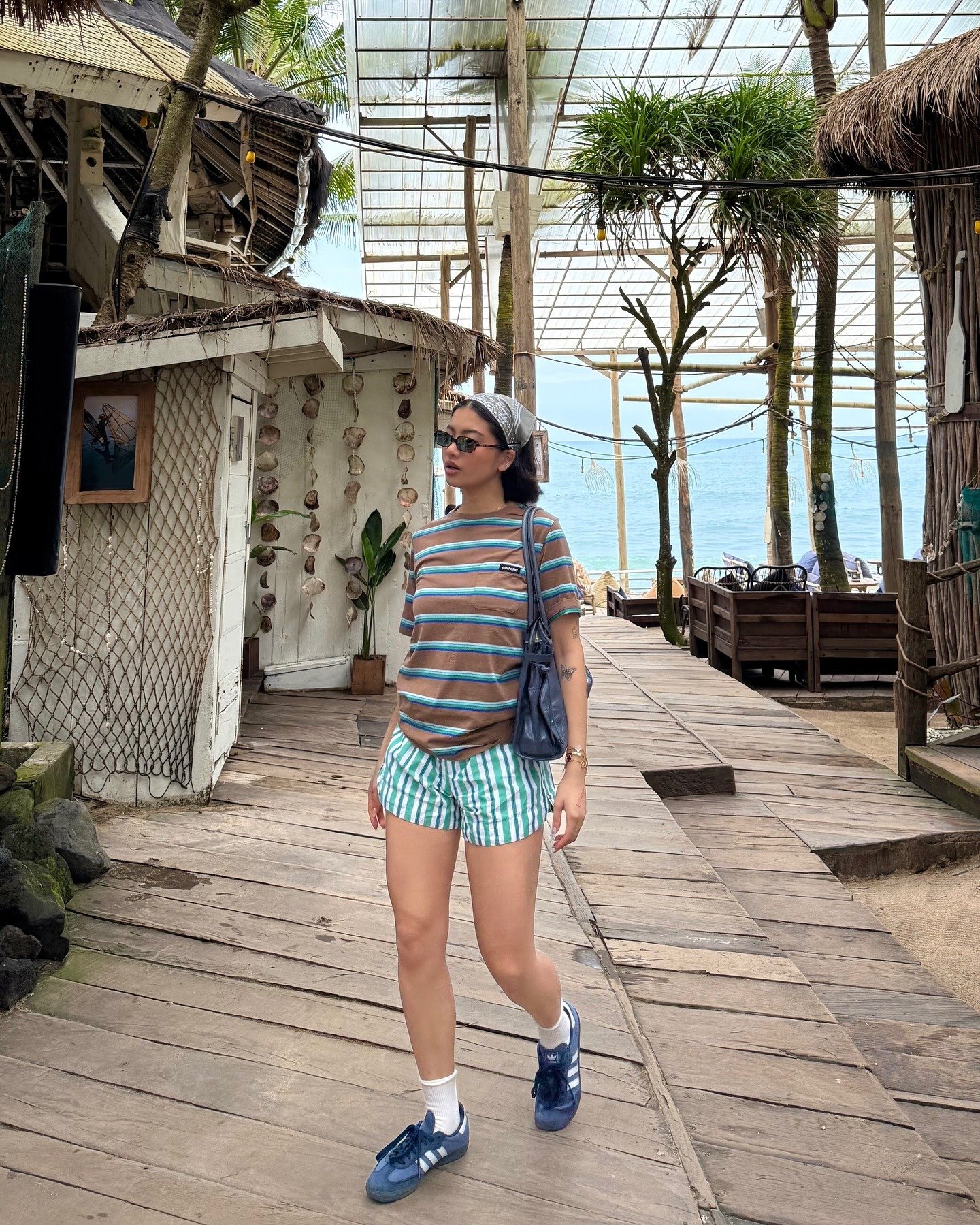 Modelo caminha com looks simples e estilosos, combinando camiseta listrada marrom e azul, shorts verdes listrados