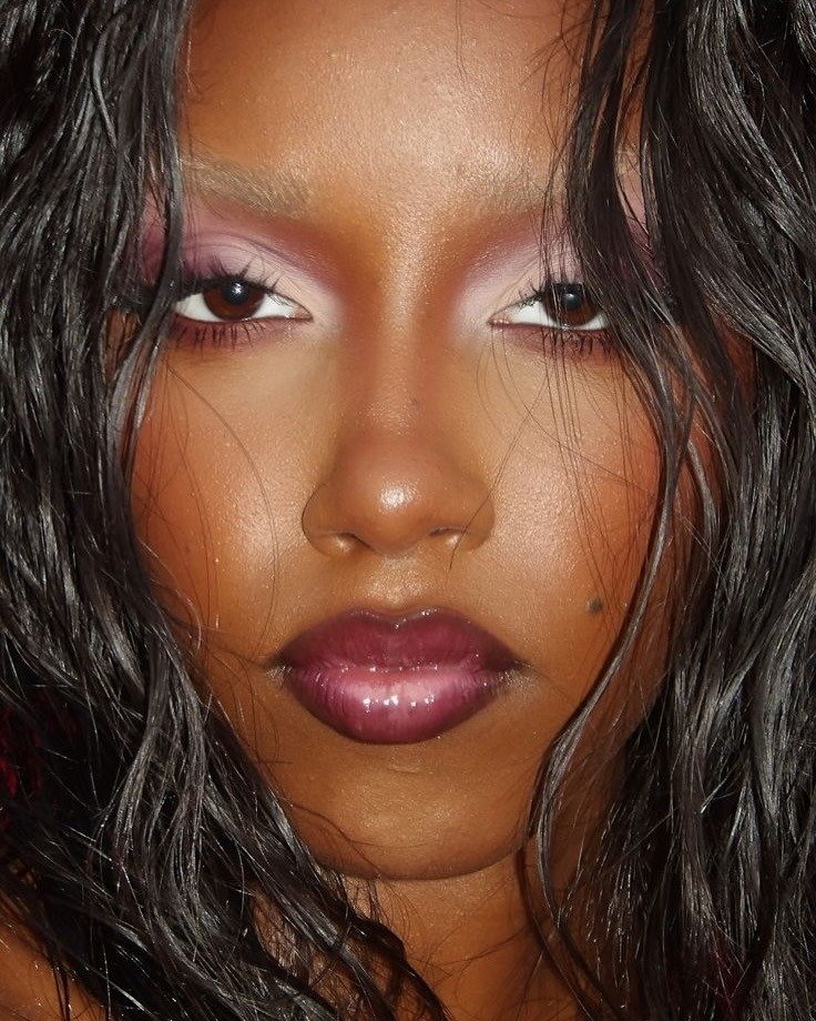 Make de carnaval com sombra rosa vibrante esfumada, delineado branco contrastante e batom vinil roxo, realçando brilho