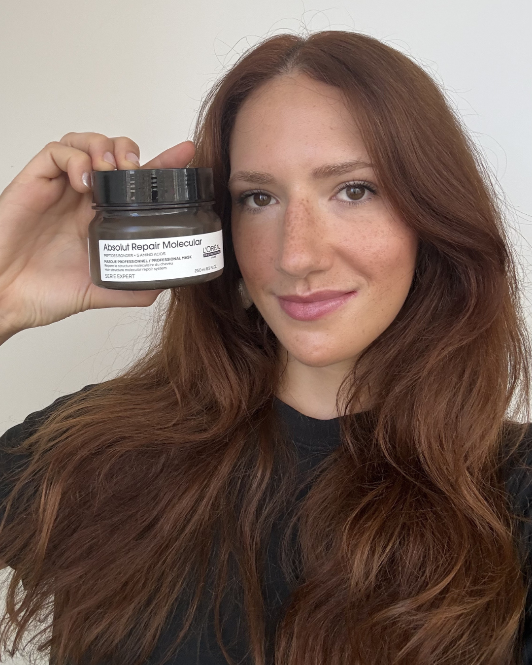 Modelo com cabelos longos e ruivos naturais segura máscara de reconstrução Absolut Repair Molecular da L’Oréal