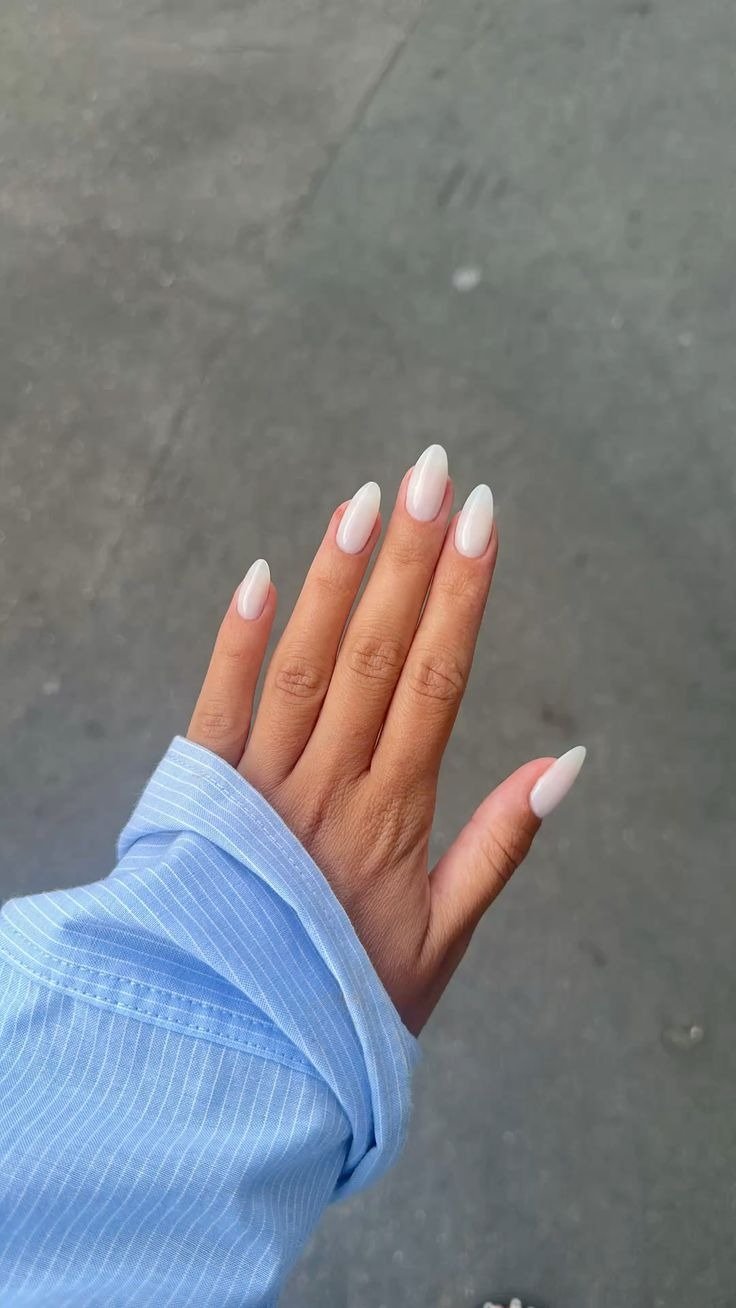 Mão com unhas longas em formato amendoado e esmalte milky nails branco leitoso, destacando elegância sutil e delicadeza, com