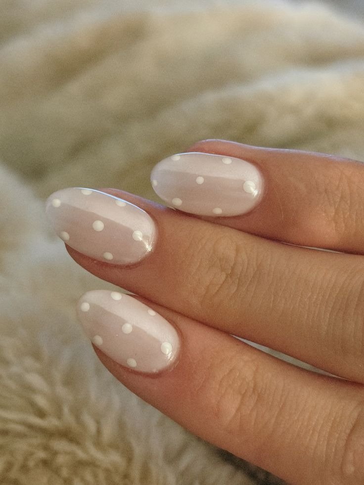 Unhas milky nails em tom leitoso com acabamento brilhante e bolinhas brancas delicadas, criando estilo suave e feminino.