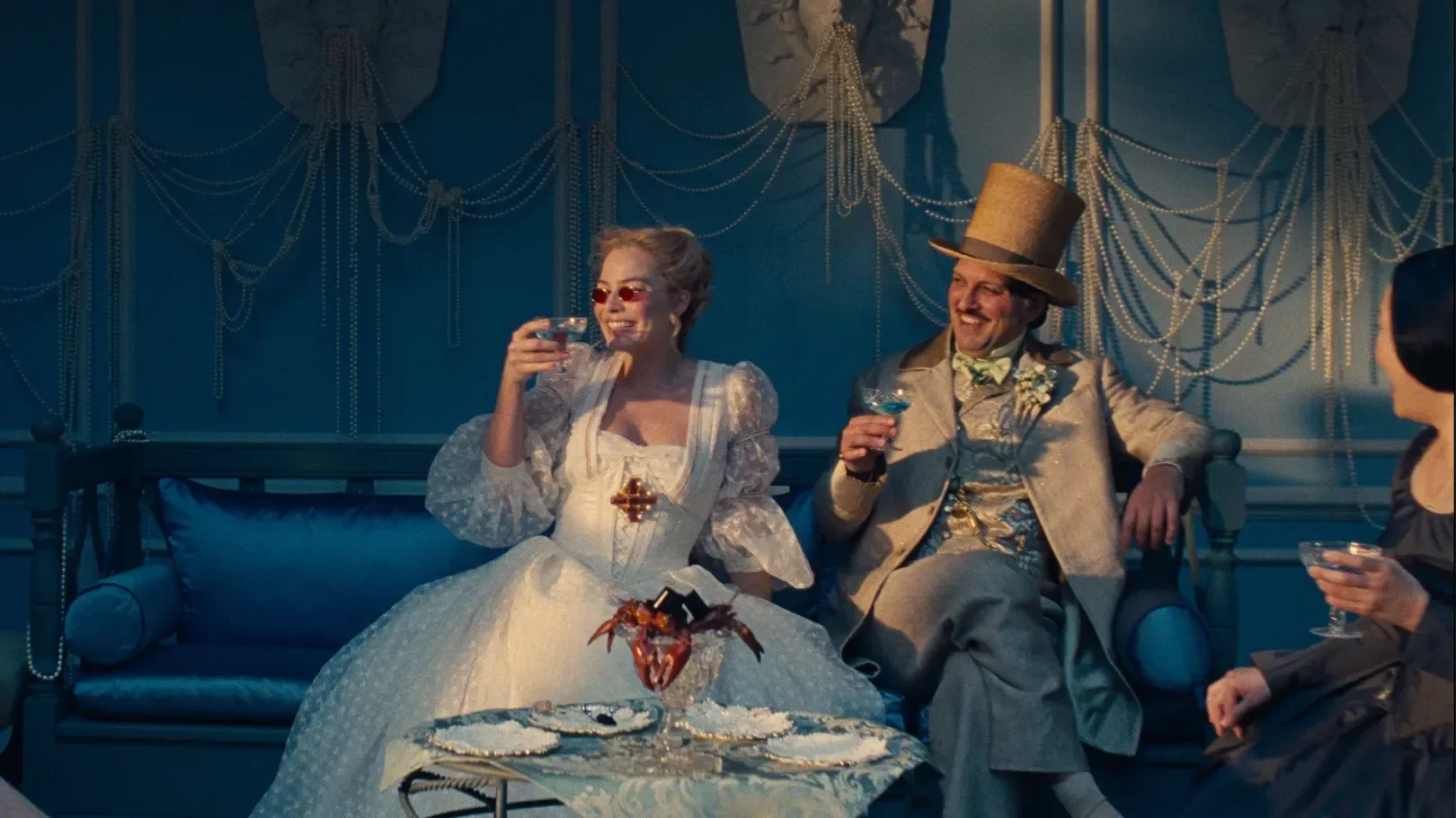 Cena de O Morro dos Ventos Uivantes mostra mulher em vestido branco de tule com mangas bufantes e homem em terno bege